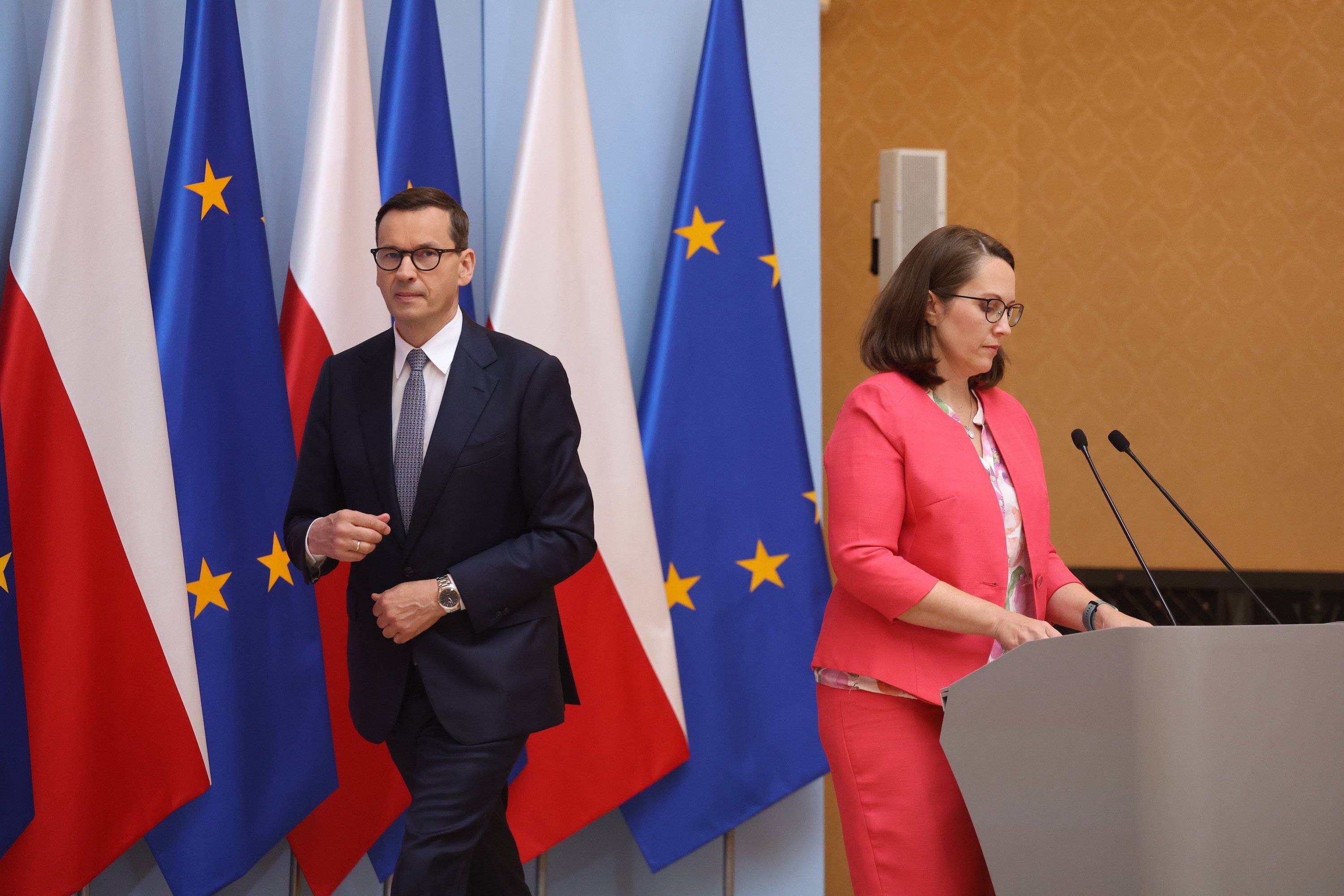 Premier Mateusz Morawiecki i minister finansów Magdalena Rzeczkowska odwróceni do siebie plecami podczas konferencji prasowej