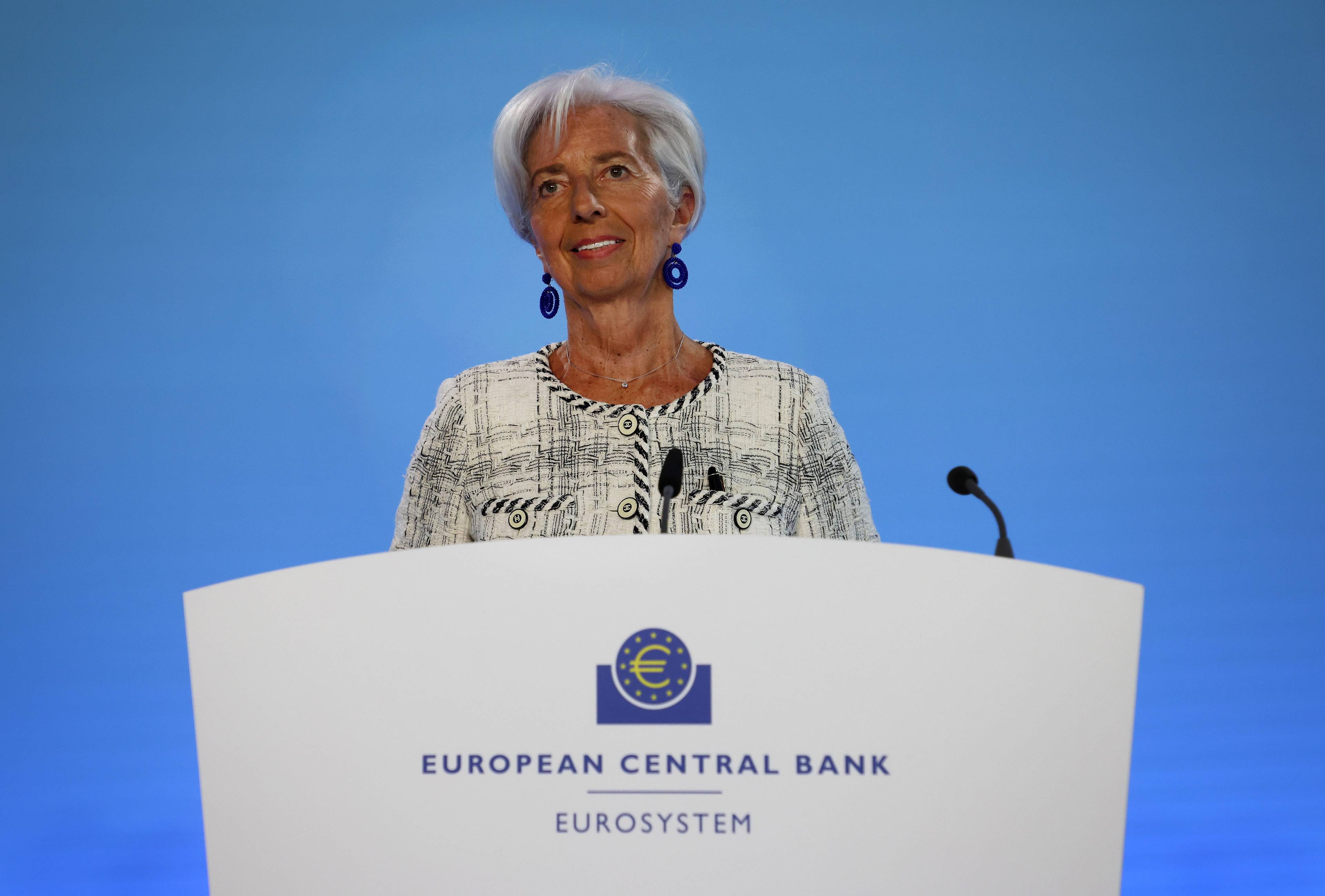 Siwowłosa kobieta w jasnej garsonce (prezeska Lagarde) przy mówinicy z logiem Europejskiego Banku Centralnego