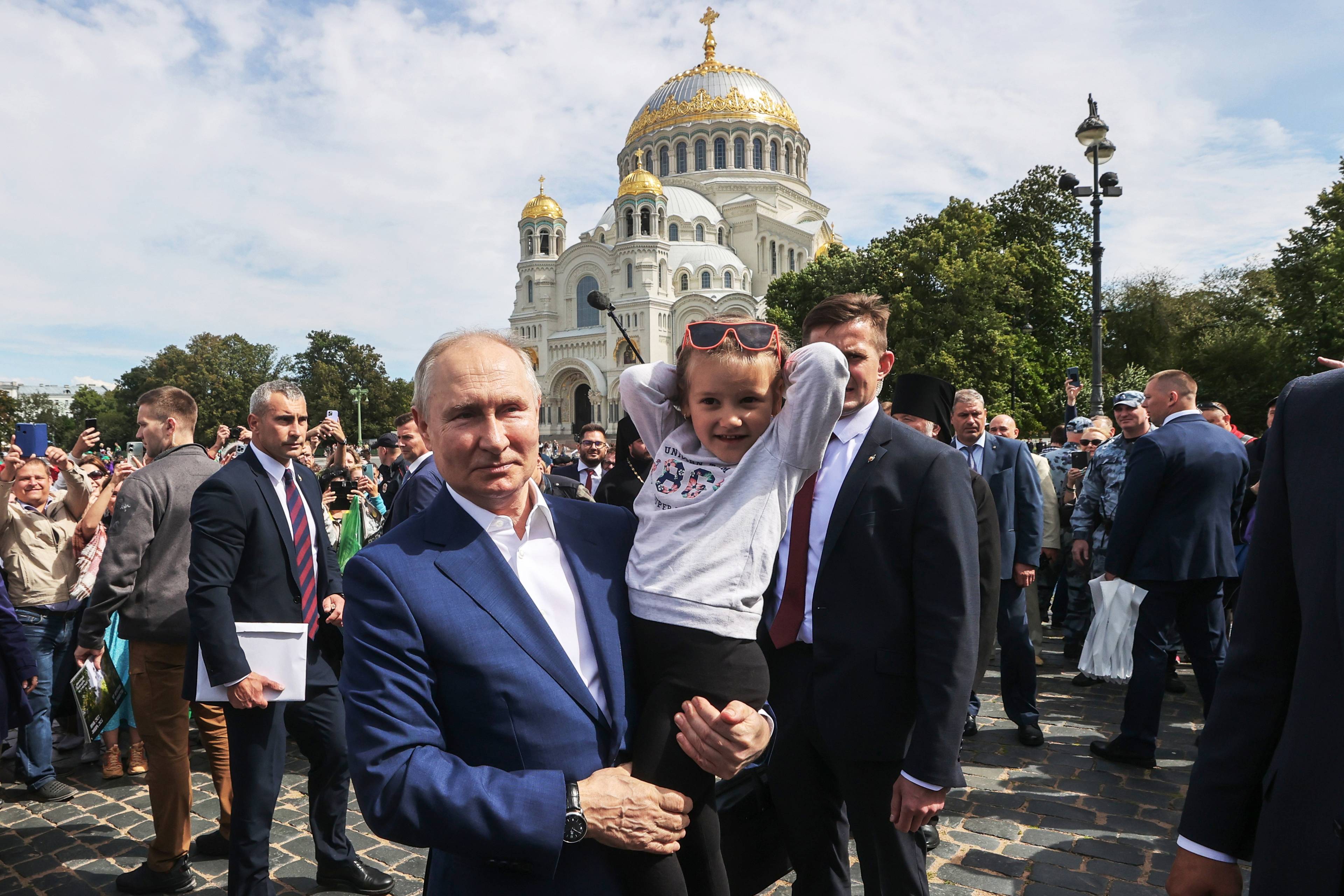 Putin stoi przed cerkwią z dziewczynka na rękach