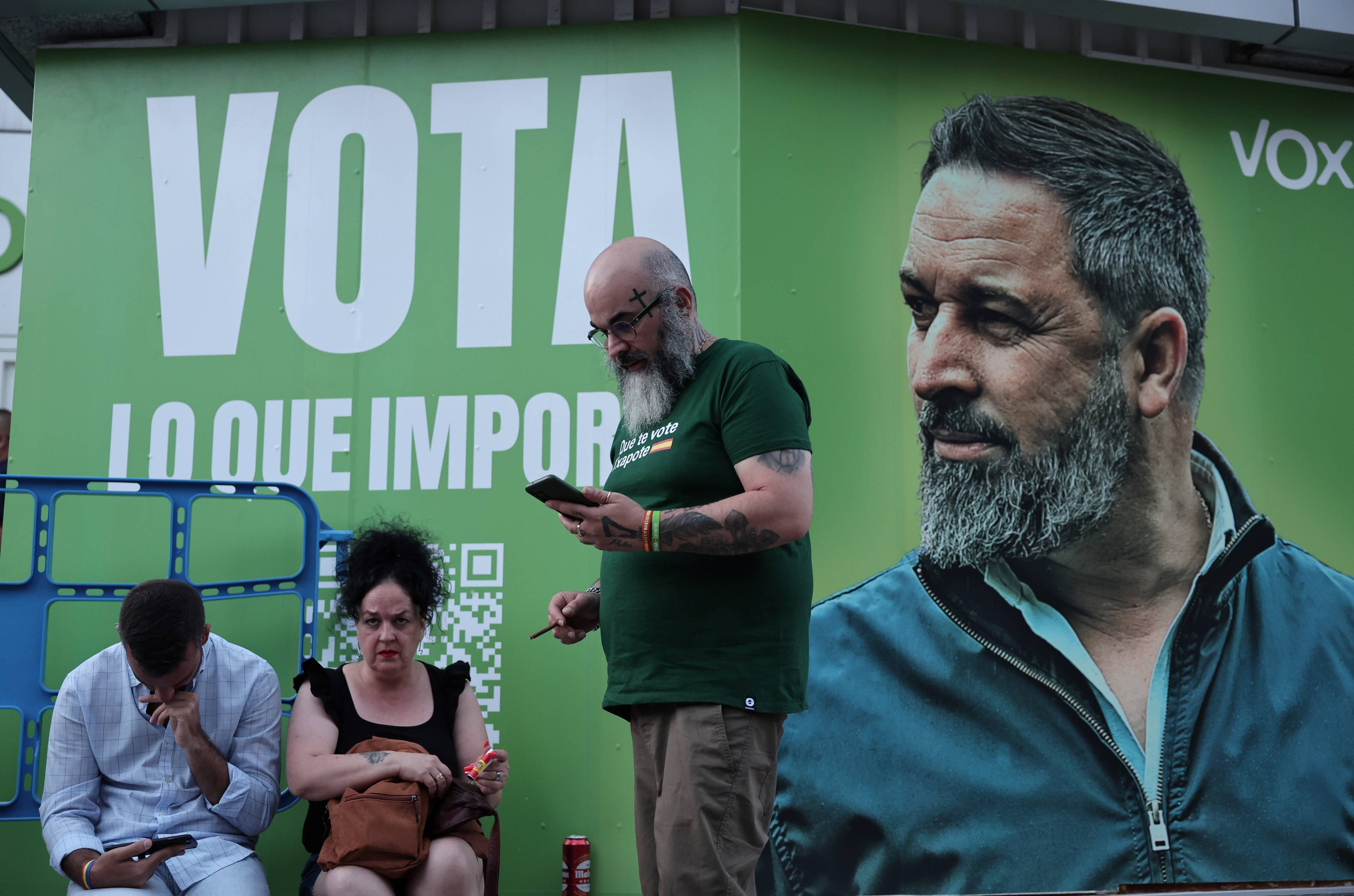 Ludzie na tle zielonego plakatu z brodatym mężczyzną