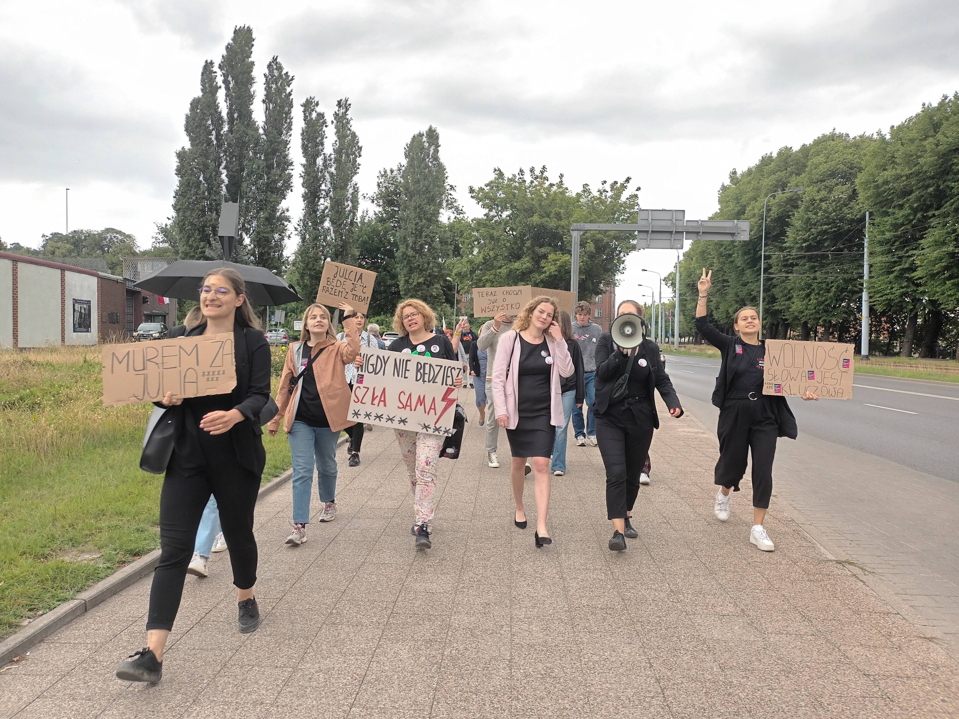 Grupa kobiet i mężczyzn z transparentem "Nigdy nie będziesz szła sama" idzie ulicą