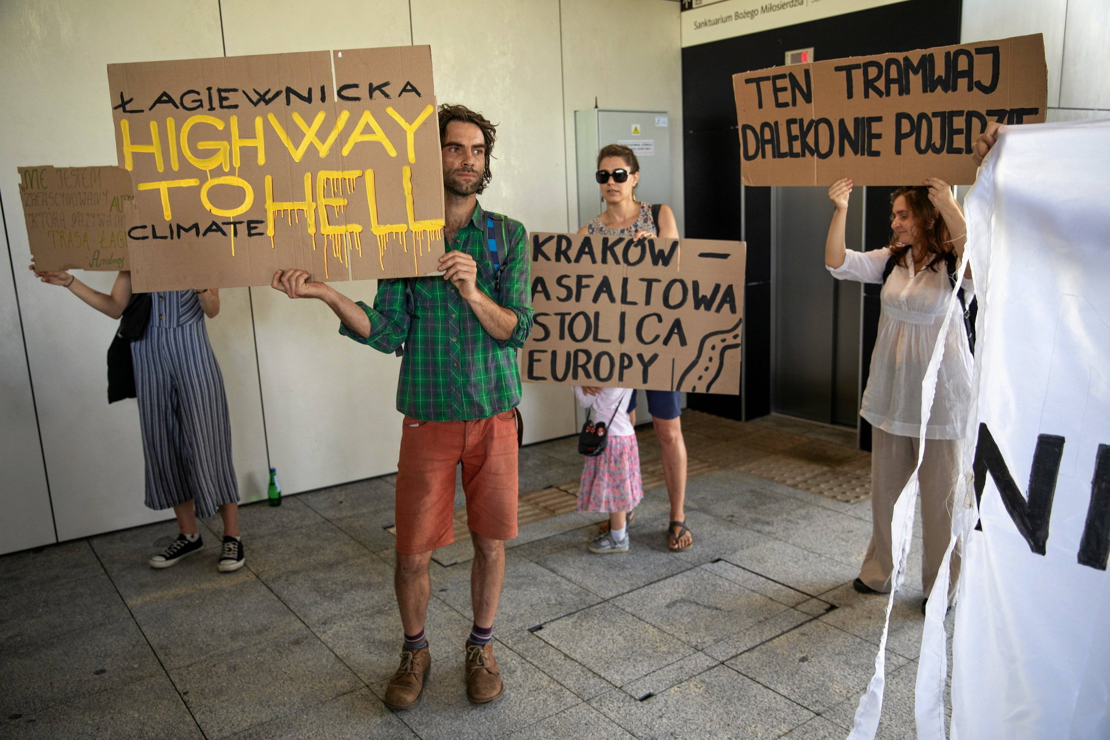 aktywiści trzymający kartony z hasłami przeciwko Trasie Łagiewnickiej
