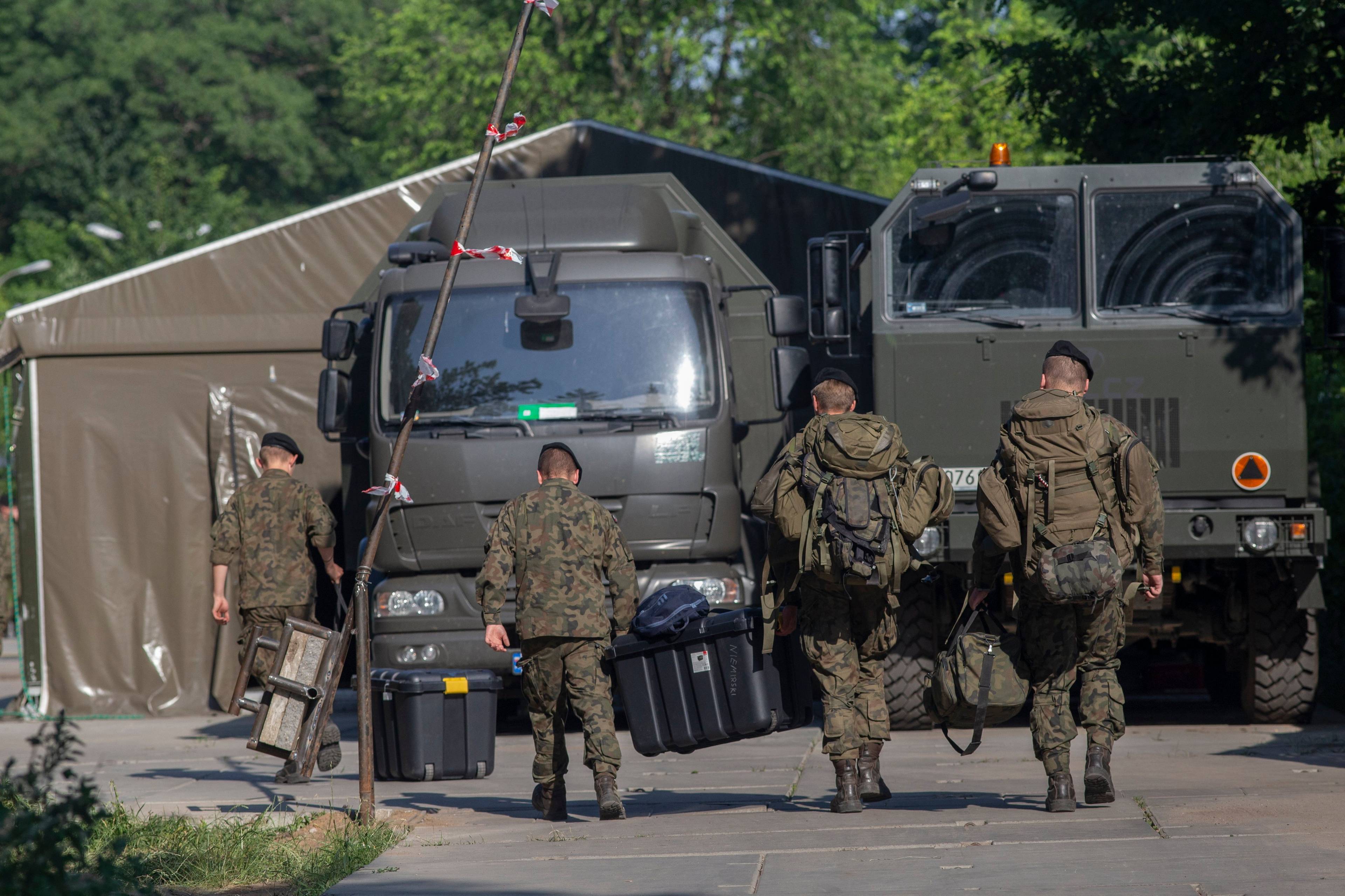 Żołnierze w mundurach idący do wojskowych ciężarówek w Białowieży (zdjęcie od tyłu)