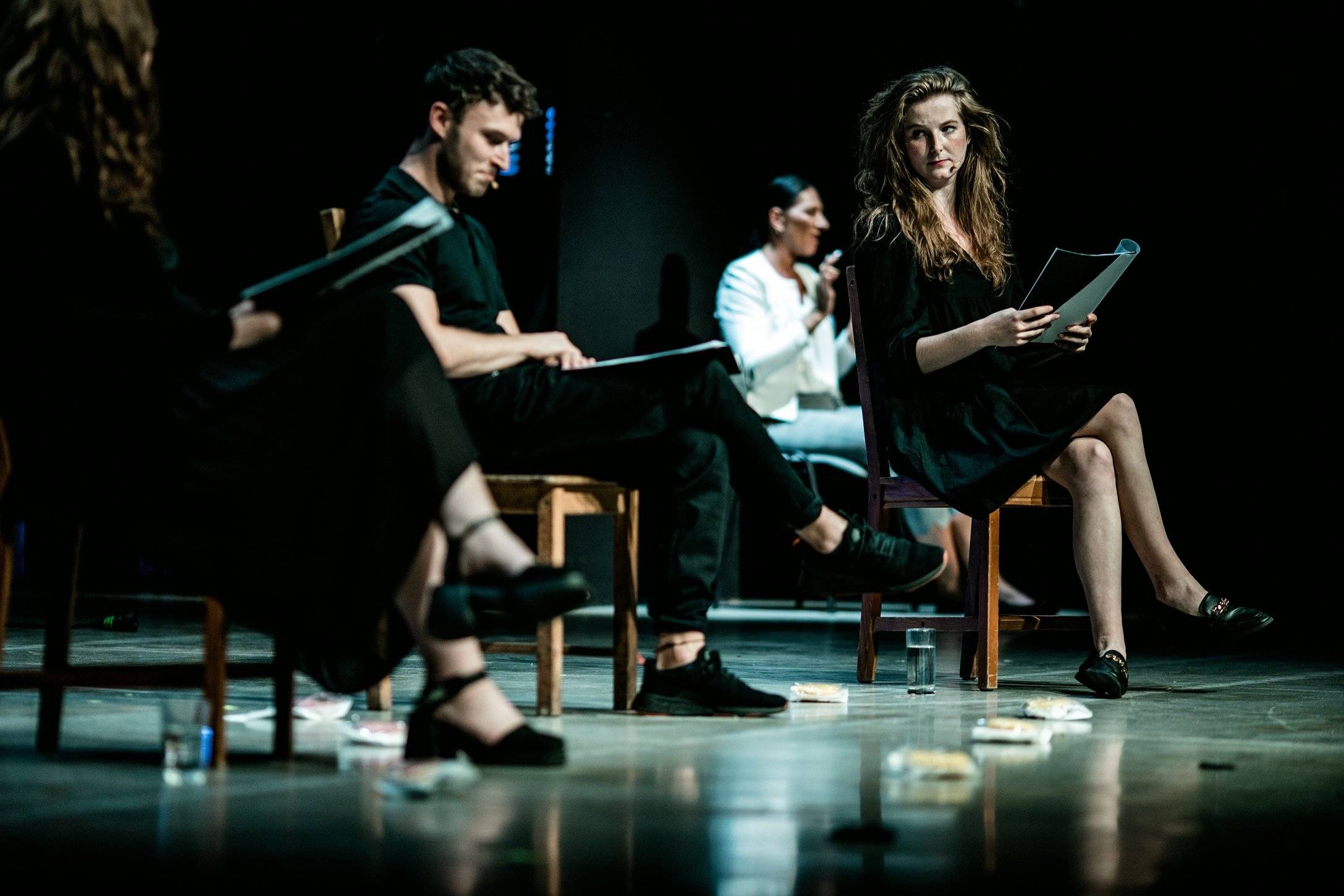 Aktoirzy czytają tekst na scenie. na podłodze leżą pączki