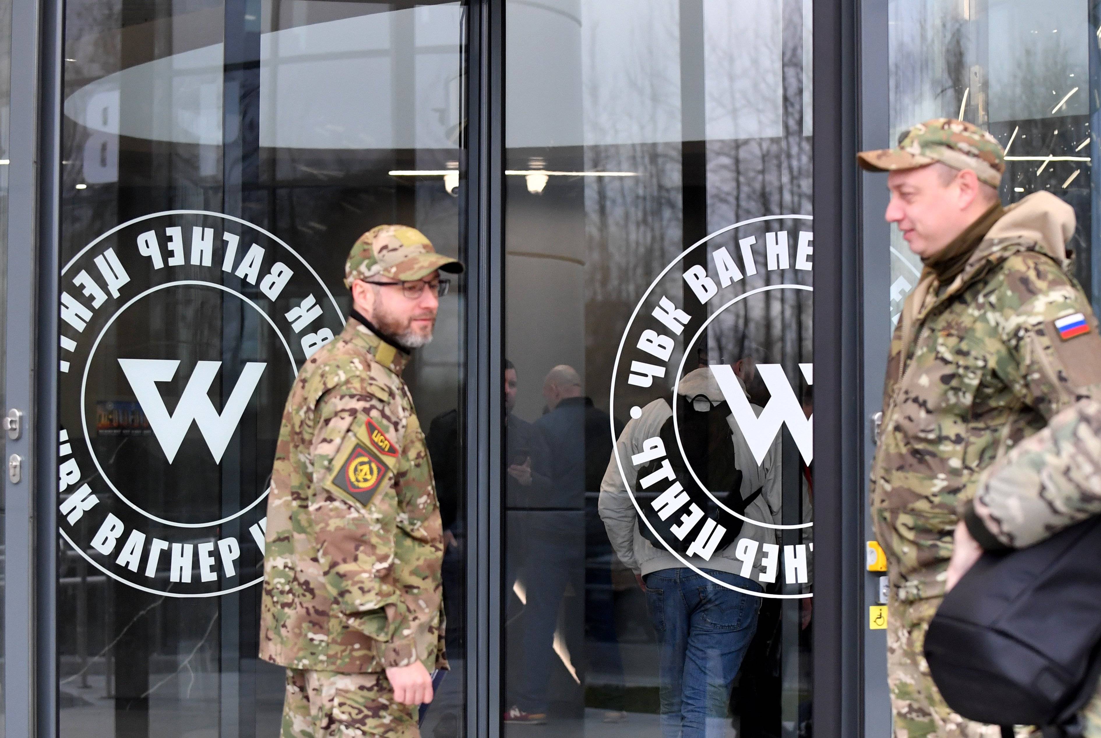 Mężczyzna w uniformie wojskowym przechodzi przez drzwi z napisem Wagner