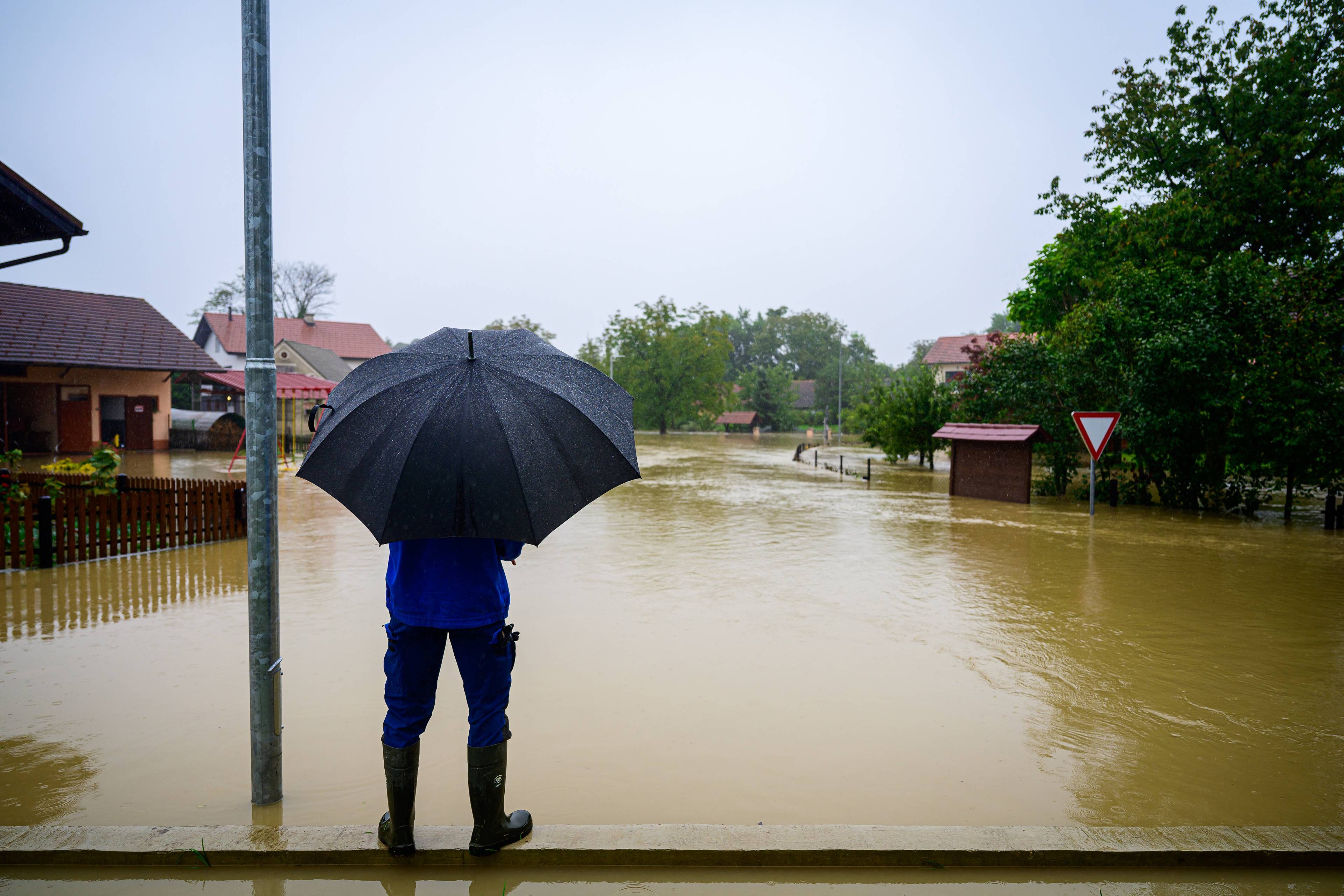 mężczyzna z parasolem patrzy w kierunku zalanej miejscowości