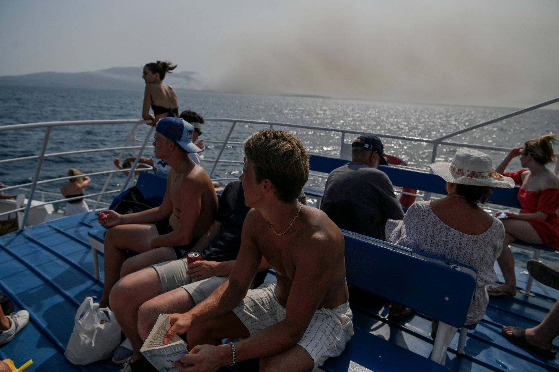 Prom z turystami na pokładzie płynie, w tle niebo zasnute dymami pożarów