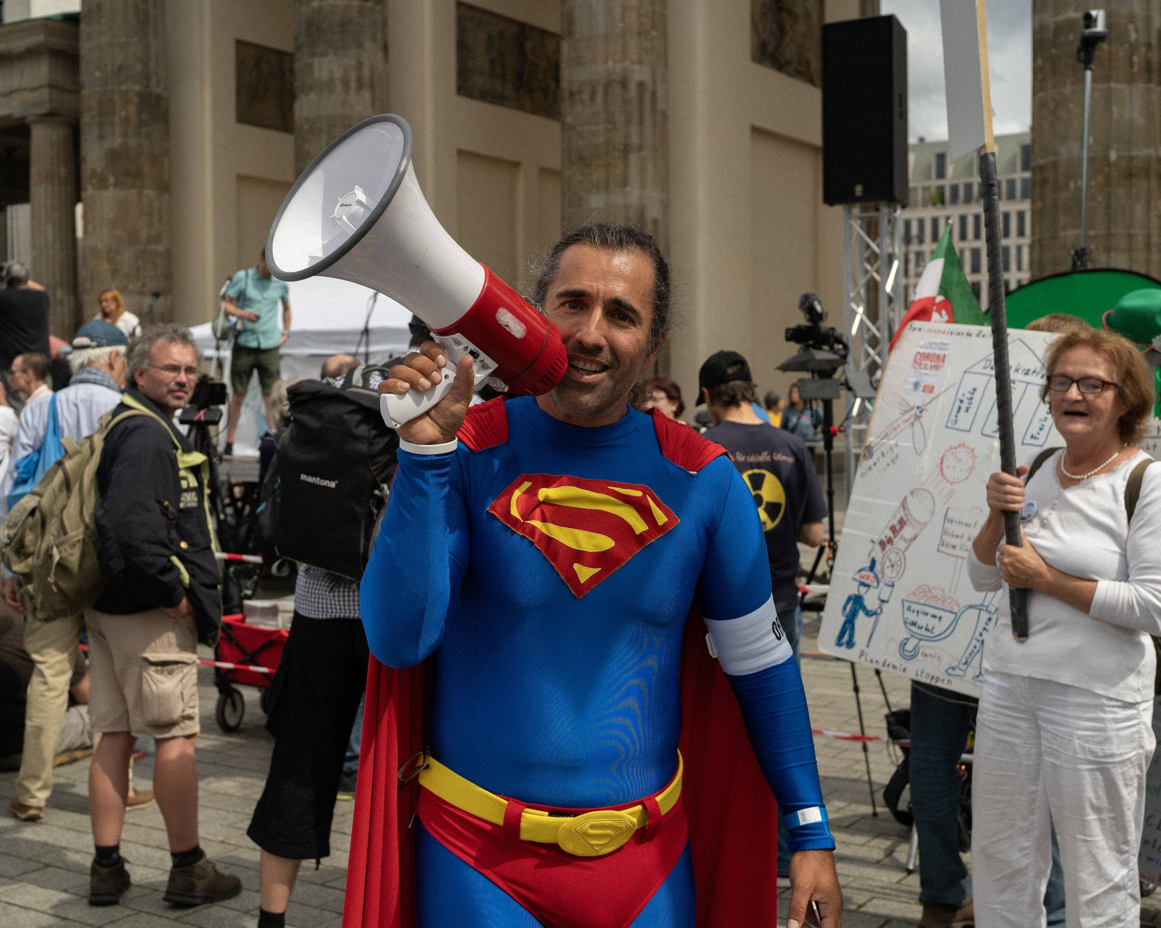Mężczyzna w stroju supermena mówi przez megafon