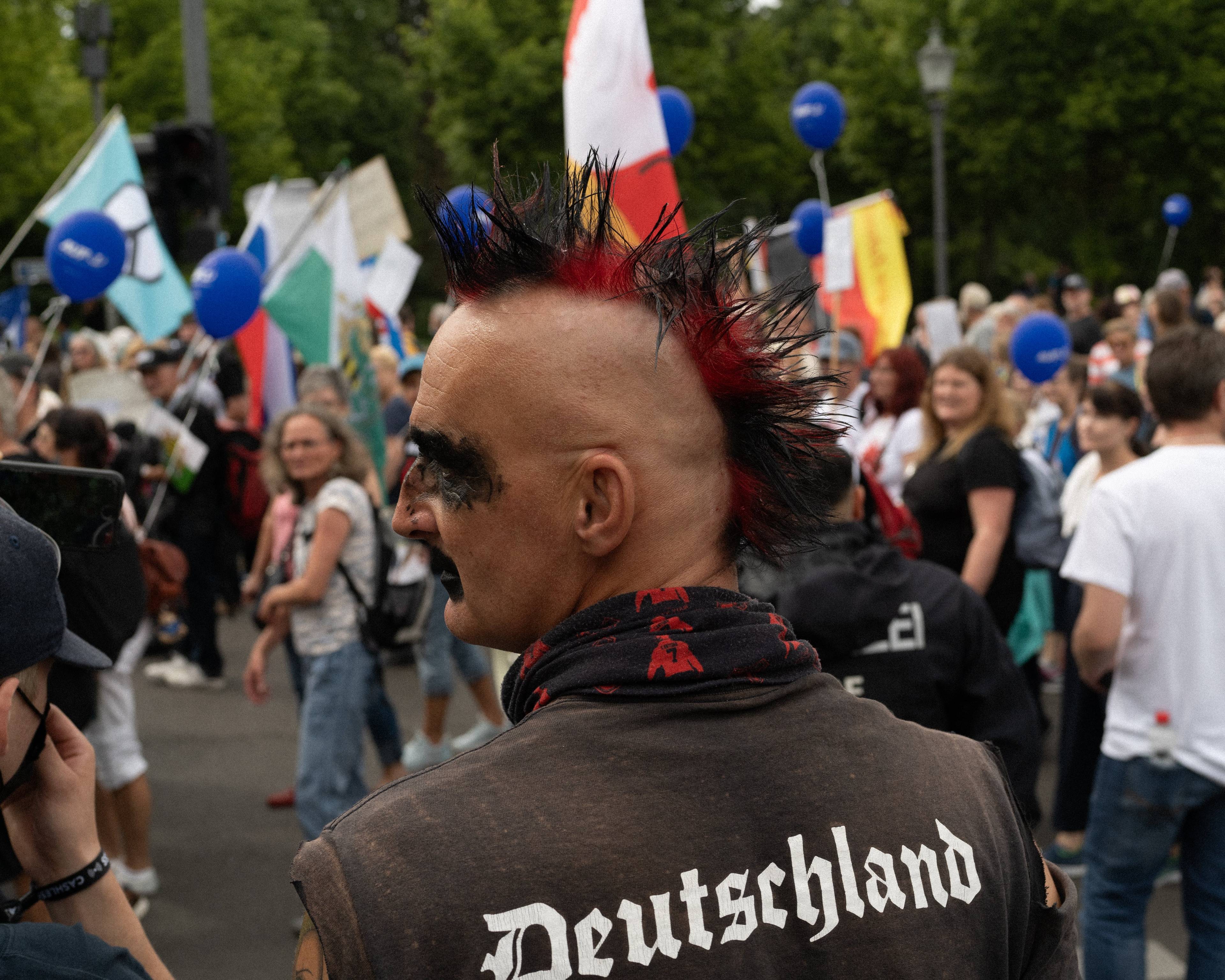 Mężczyzna z kolorowym irokezem na wygolonej głowie i napisem na plecach "Deutschland"