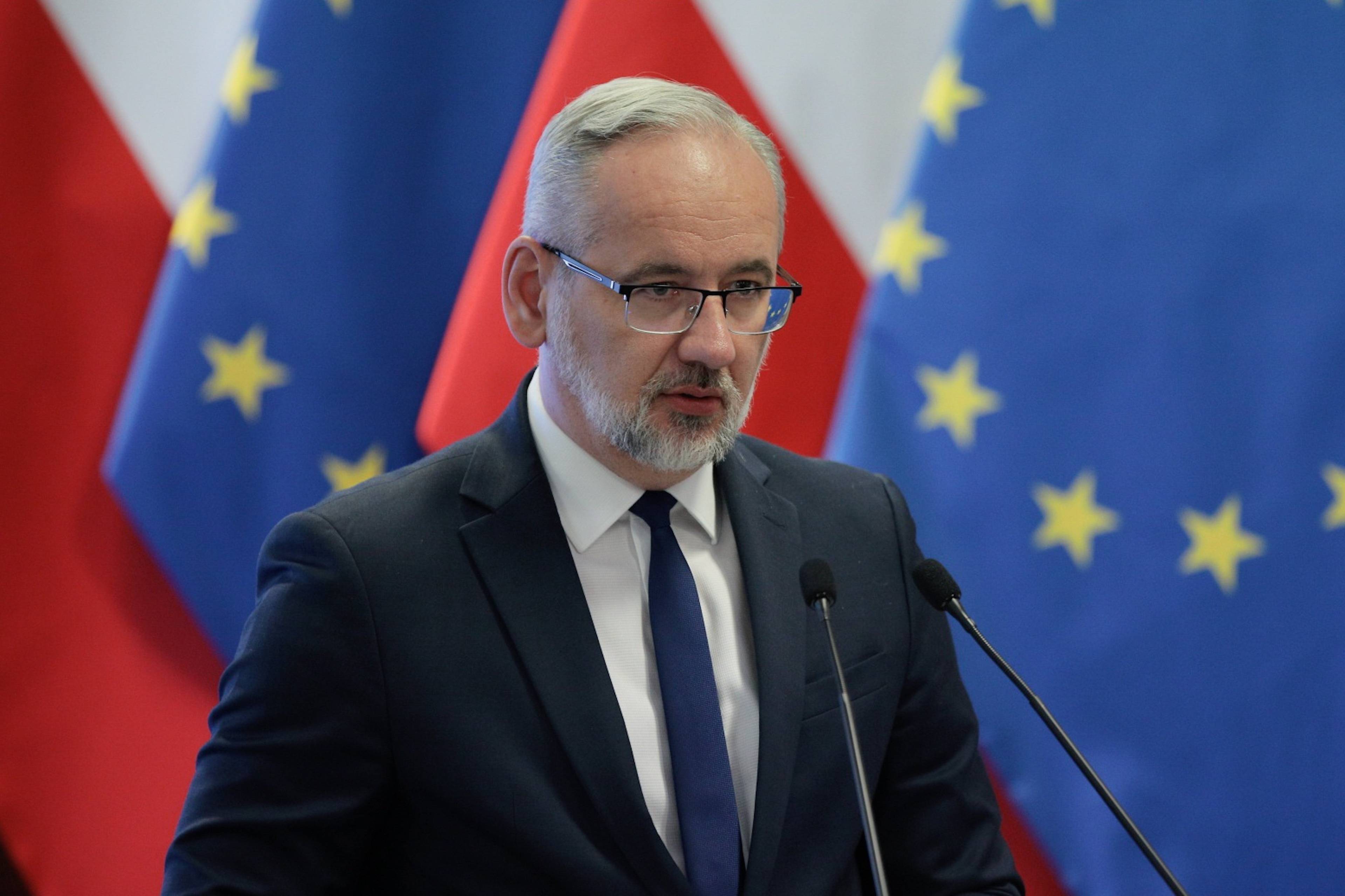 Adam Niedzielski przemawia na tle flag Polski i UE