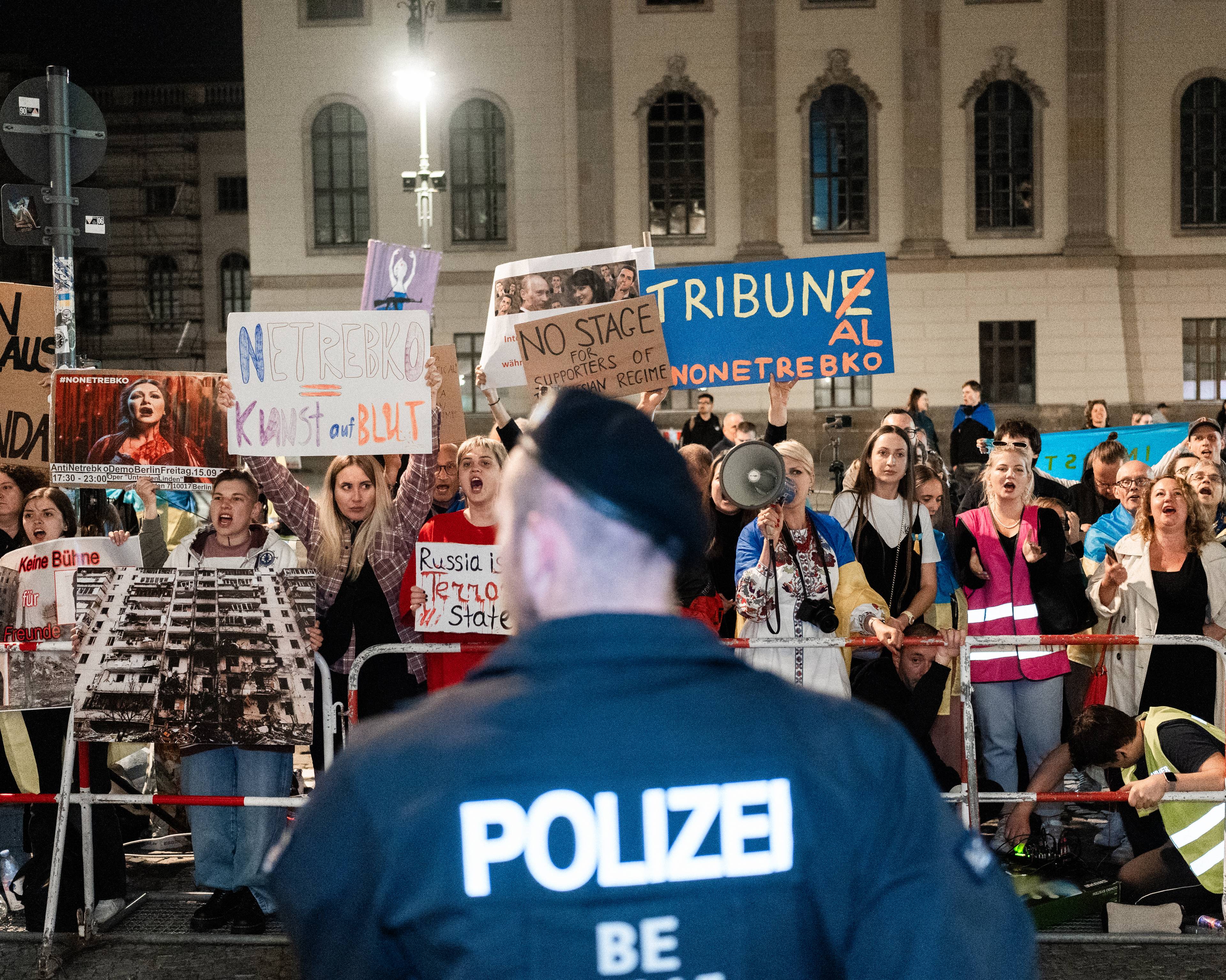 zdjęcie z protestu ulicznego, na pierwszym planie plecy niemieckiego policjanta