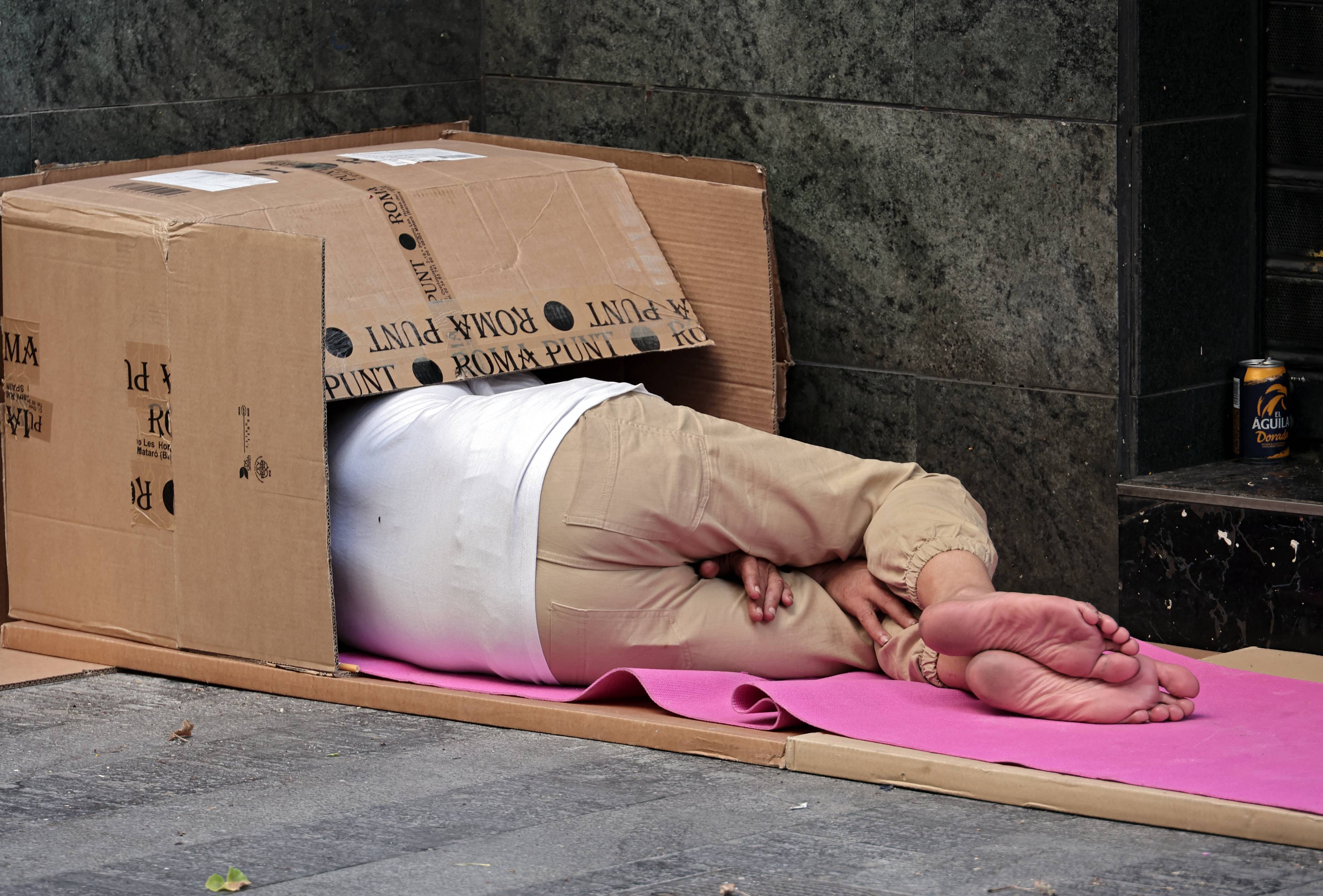 Bezdomny śpiący w kartonie na ulicy