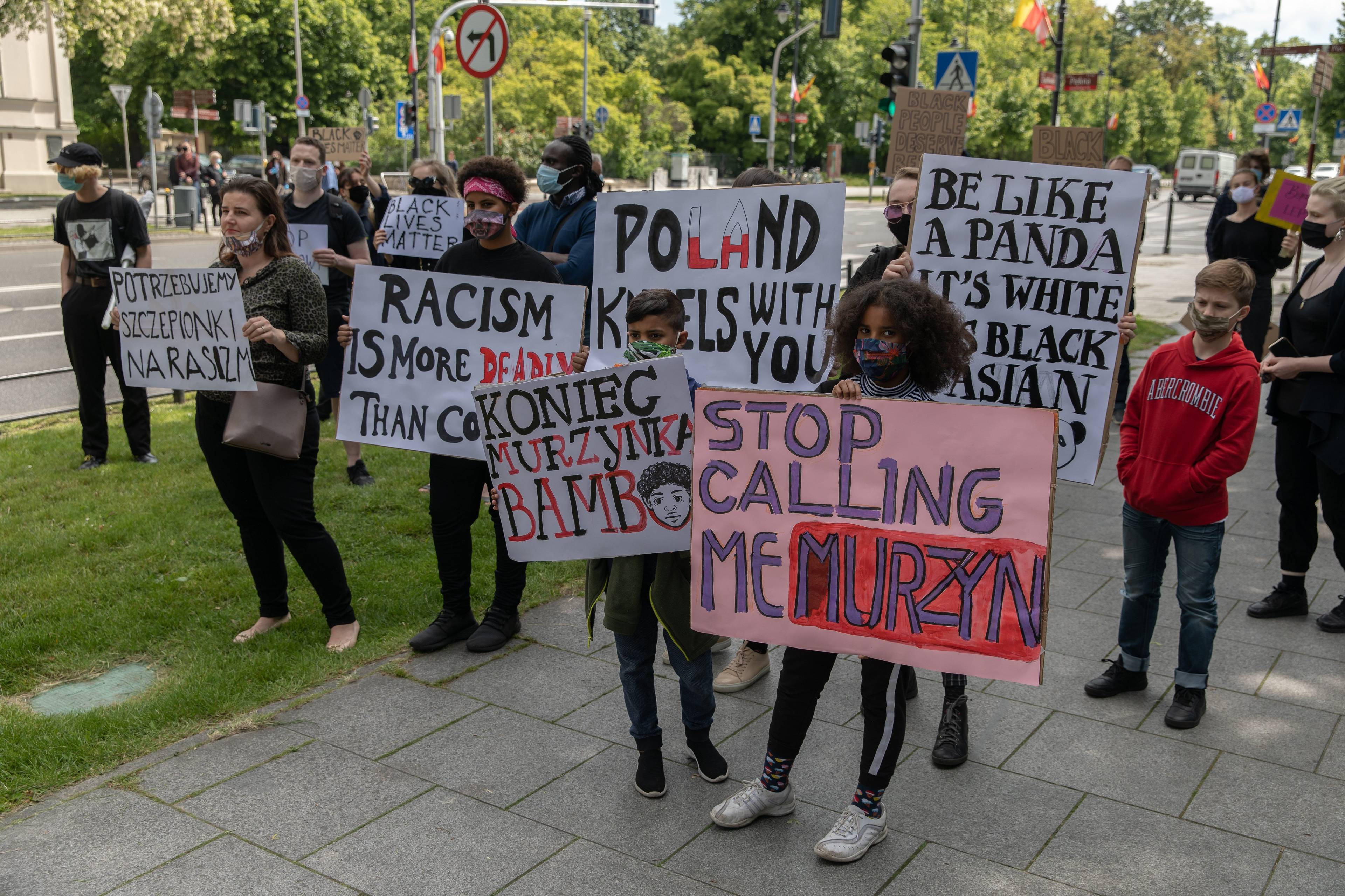 Demonstranci na ulicy trzymają plansze z hasłami przeciwko rasizmowi: „Stop Calling me Murzyn”, „Koniec Murzynka Bambo”