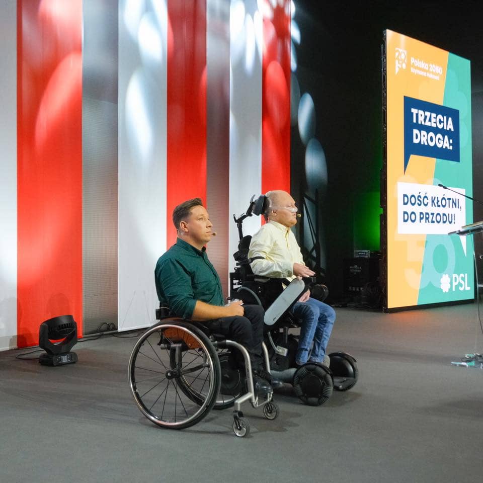 Dwaj męzczyźni na wózkach inwalidzkich prowadzą prezentację pod hasłem Trzecia Droga