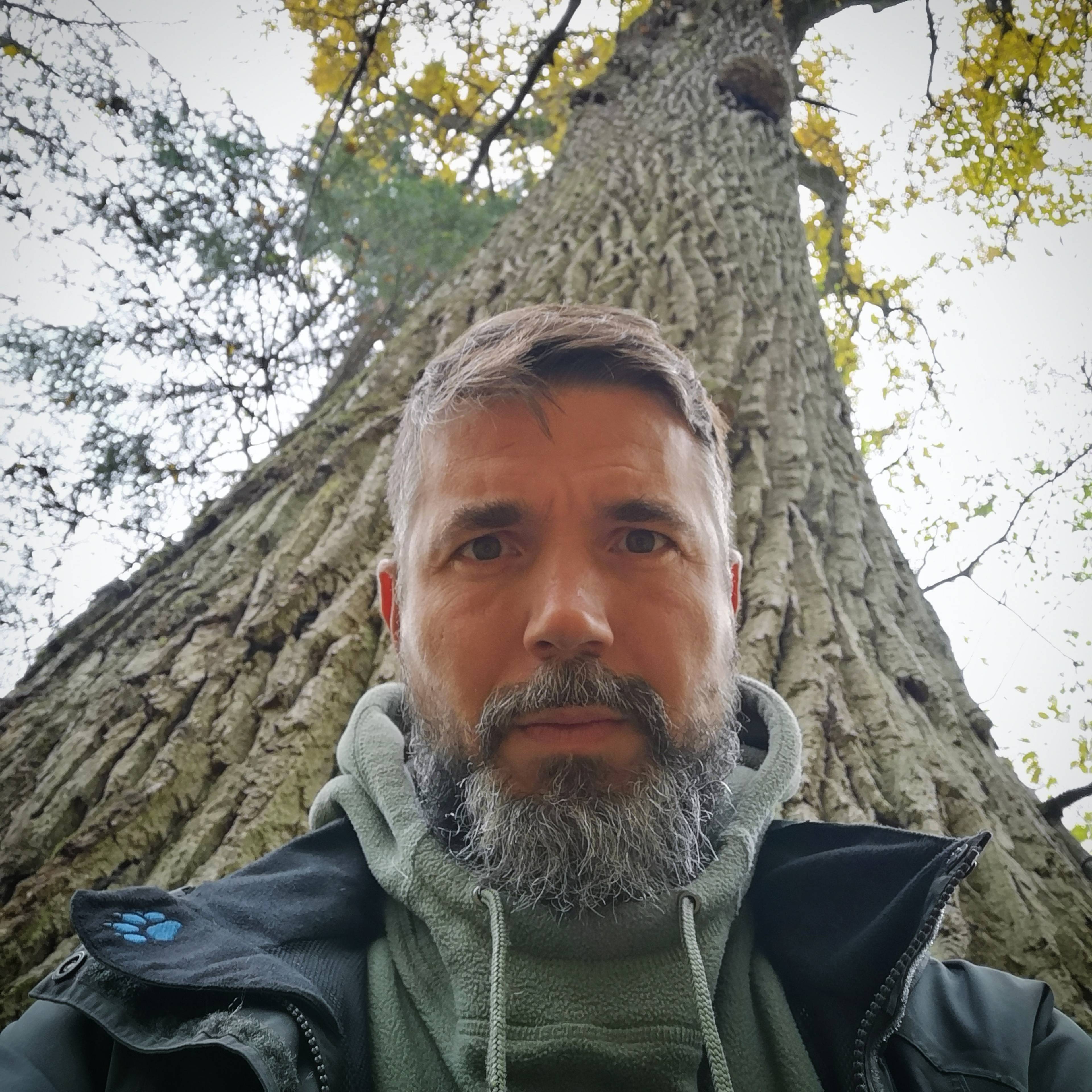 Mężczyzna sfotografowany na tle dużego drzewa