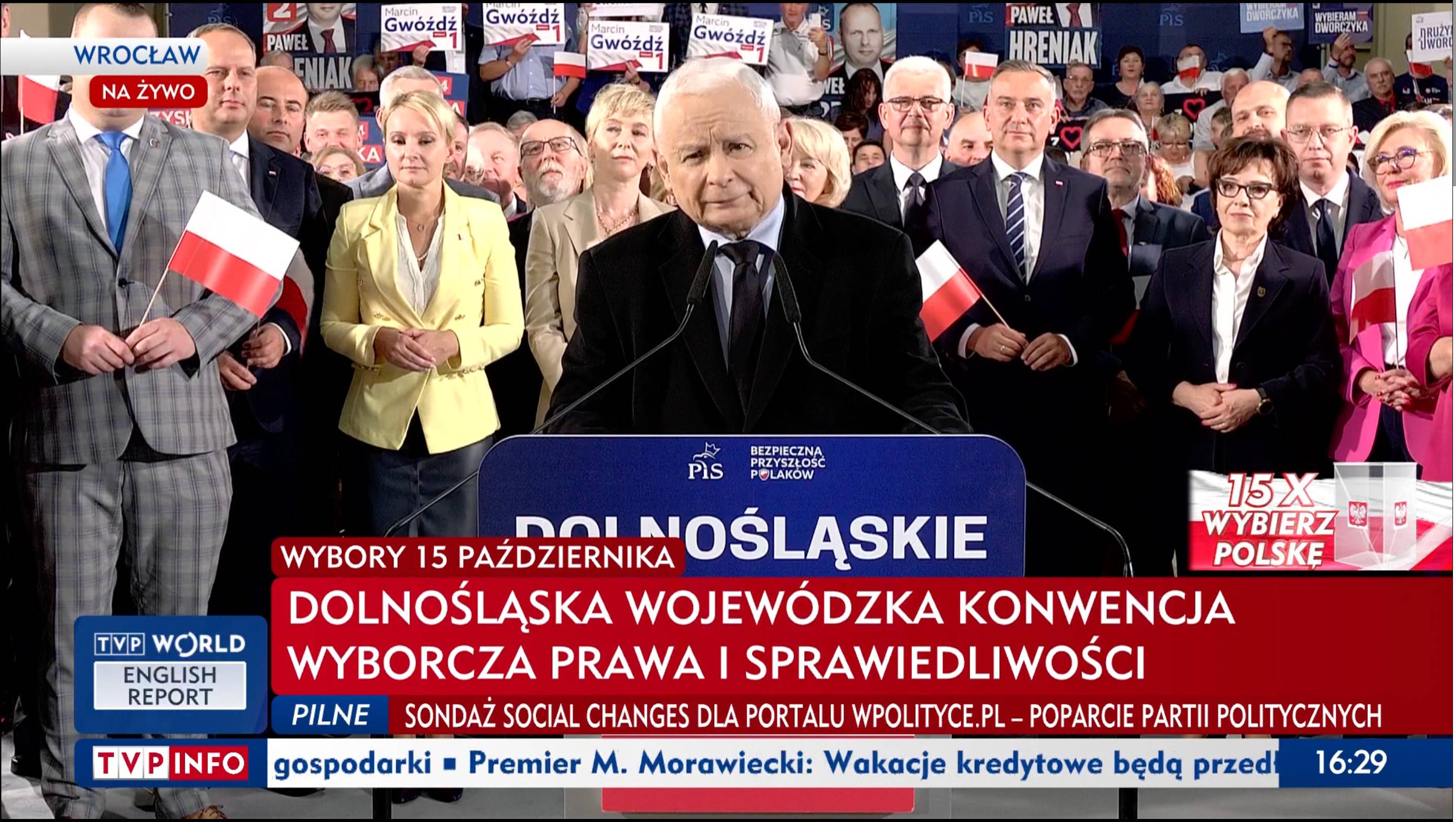 Jarosław Kaczyński przemawia z mównicy. Dookoła wianuszek działaczy i działaczek PiS