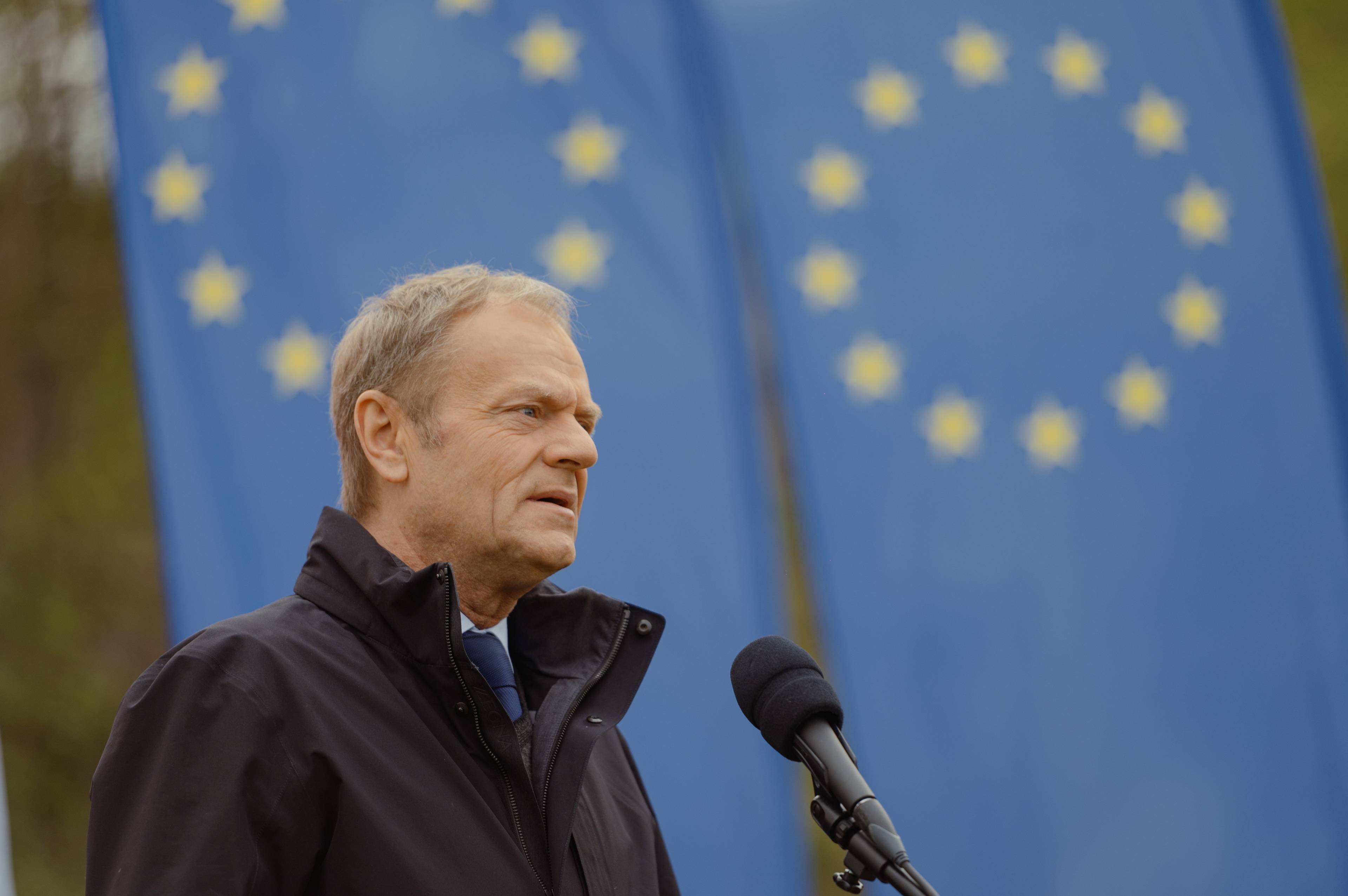 Donald Tusk na tle flag Unii Europejskiej