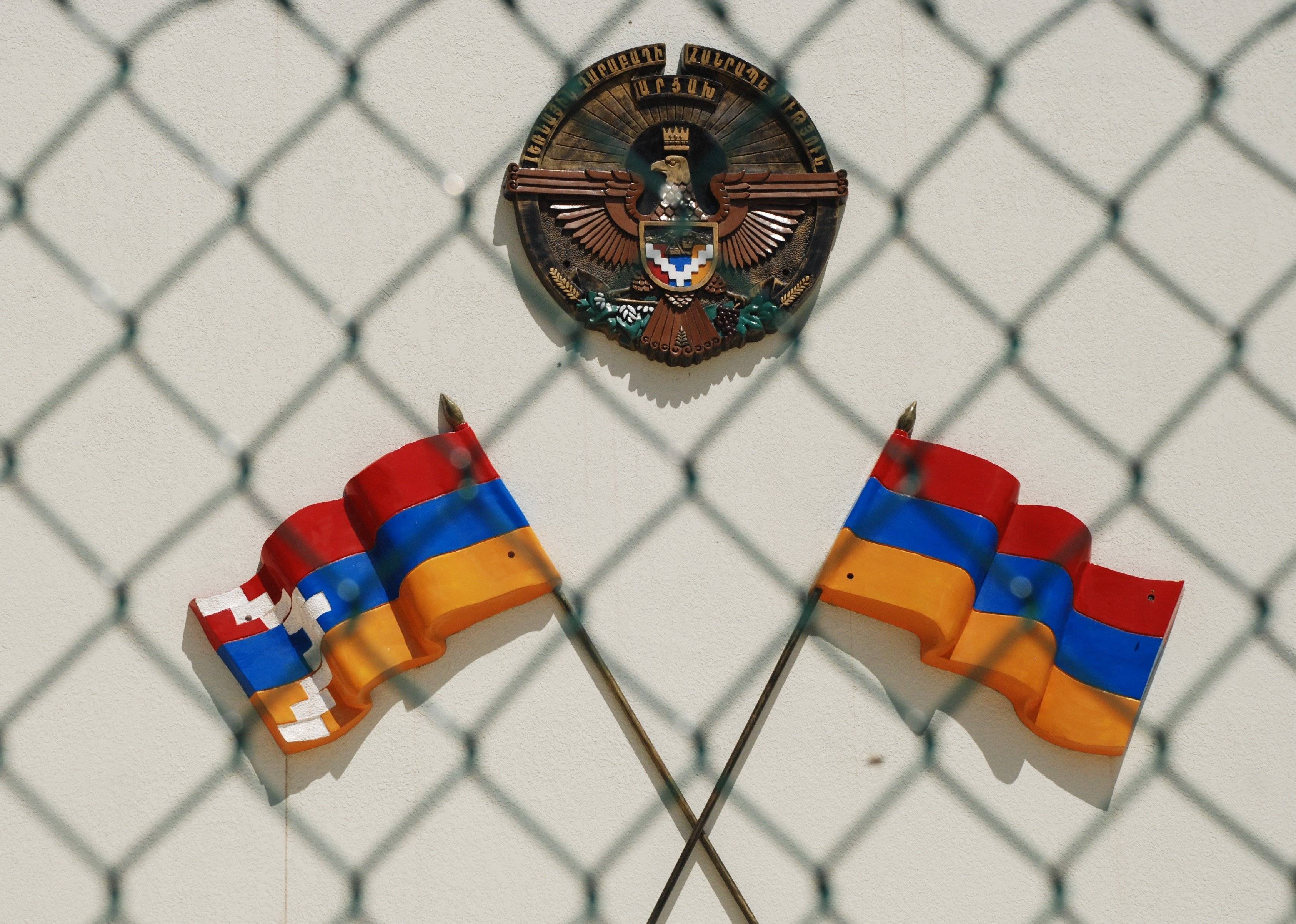 Dwie skrzyżowane niemal identyczne flagi, czerwono-niebiesko-pomarańczowe, karabachska i armeńska