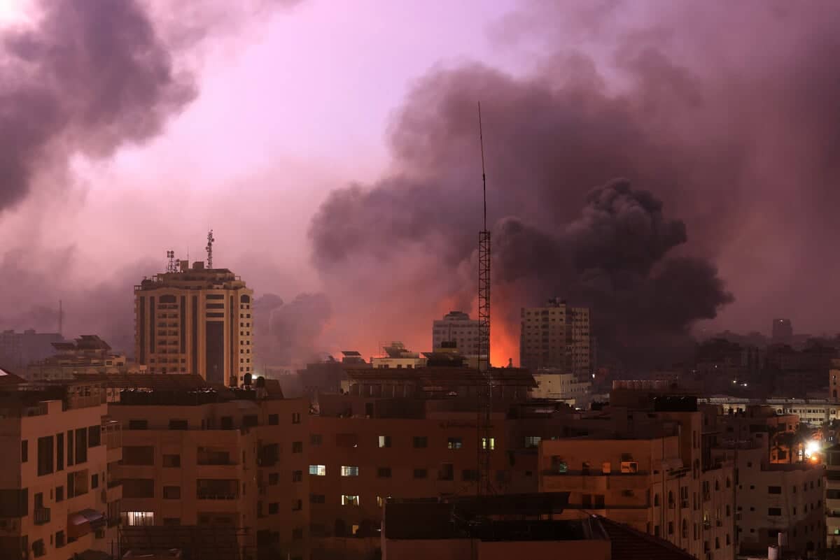 Kłeby dymu i ogień pożarów nad budynkami na tle wieczorngo nieba