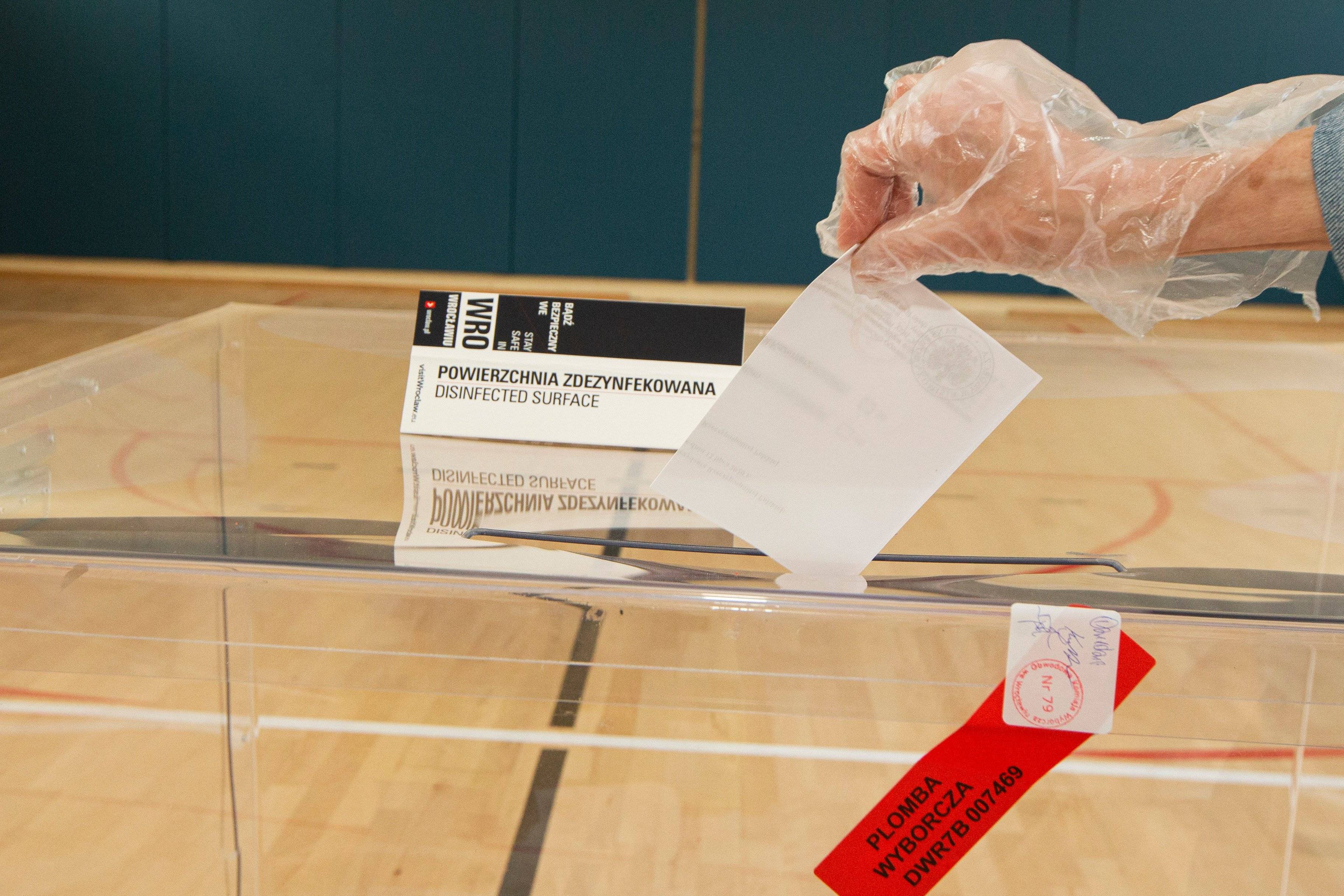 Kartka wyborcza wrzucana do przezroczystej urny wyborczej