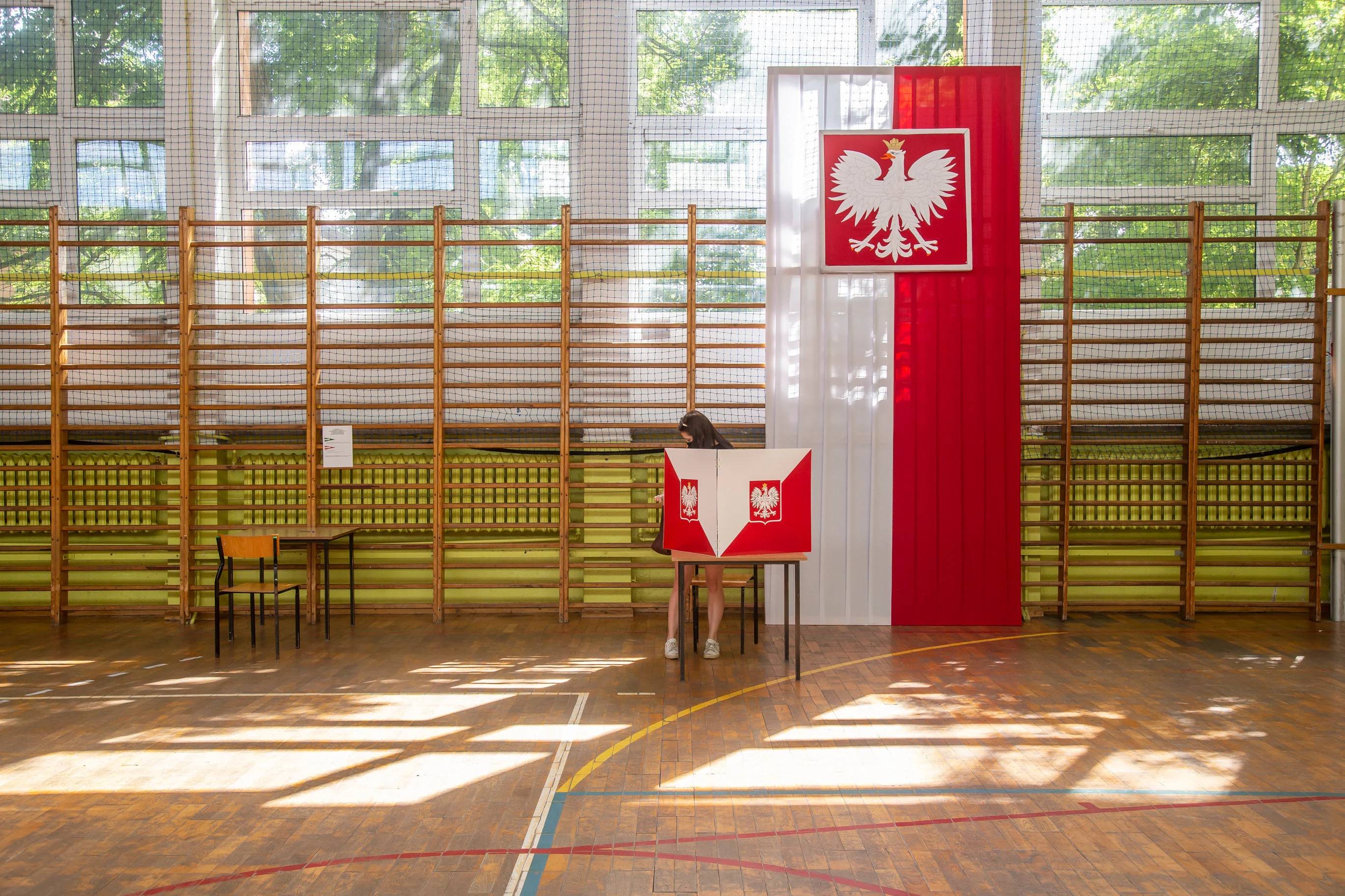 Sala szkolna, udekorowana flagą białoczerwoną, stolik do głosowania