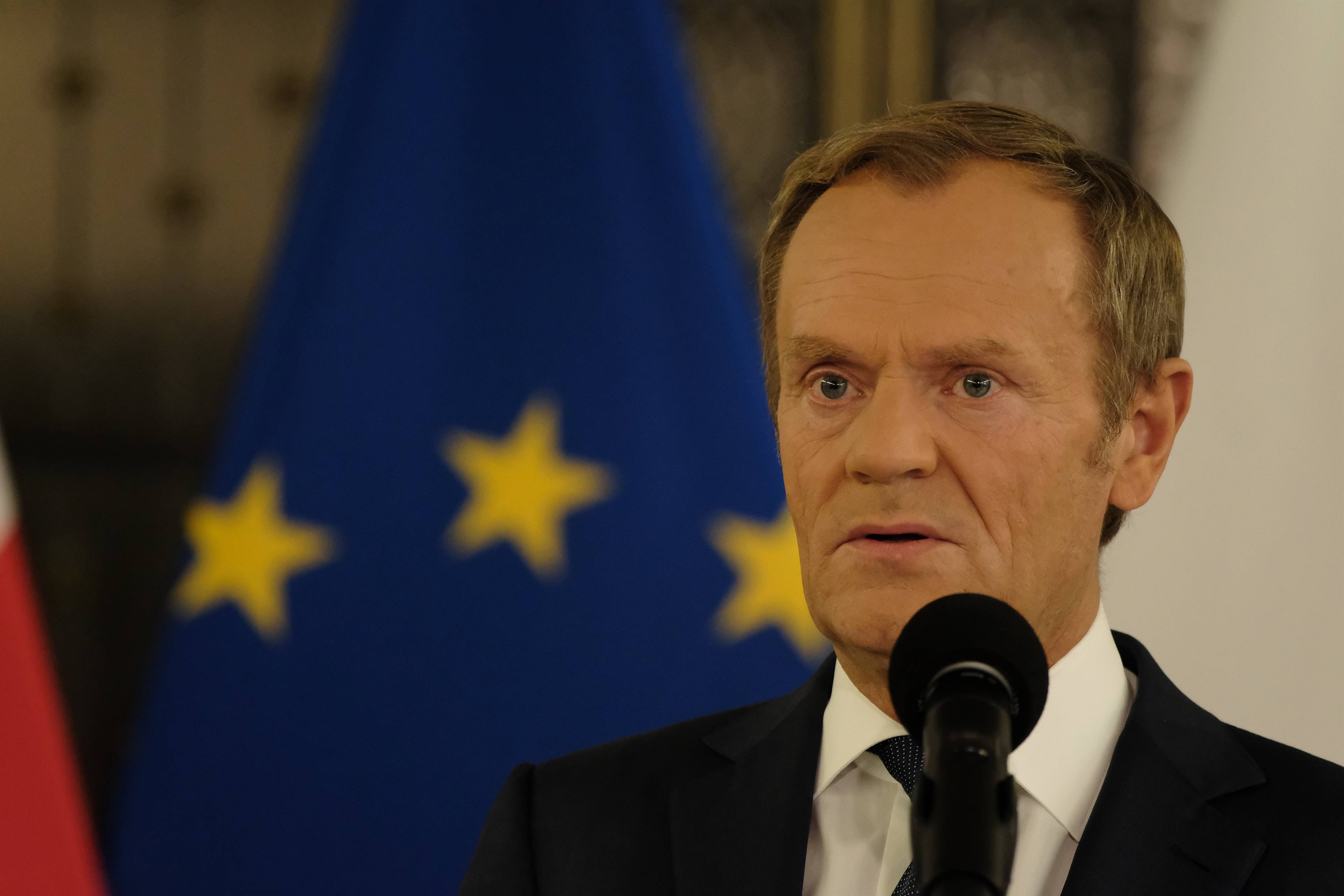 Donald Tusk na tle europejskiej flagi - granatowej ze złotymi gwiazdami