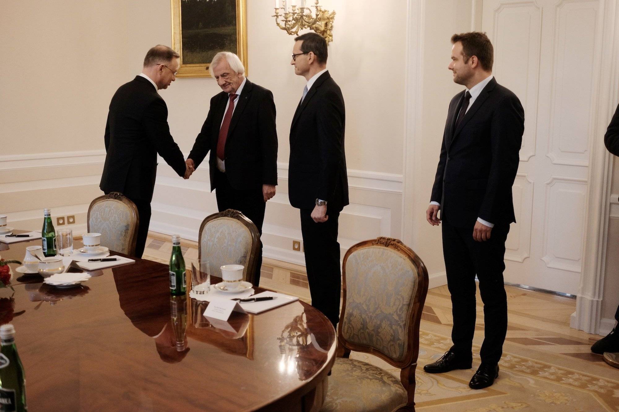 Prezydent Andrzej Duda z delegacją PiS w Pałacu Prezydenckim. Duda ściska dłoń Ryszarda Terleckiego, przyglądają się temu Mateusz Morawiecki i Rafał Bochenek.