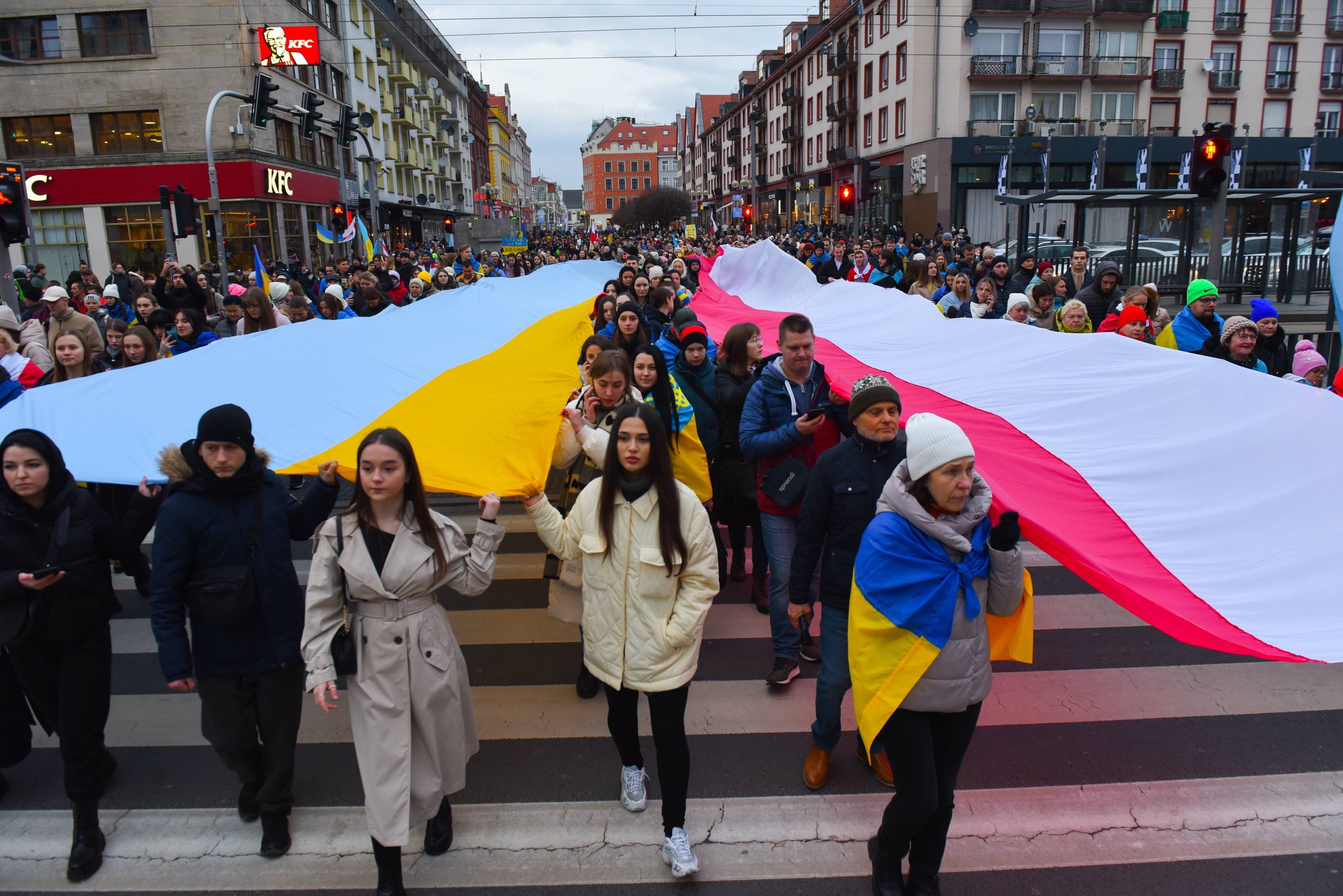Demonstracja. Ludzie niosą dwie wielkie flagi (tzw. sektorówki): polską i ukraińską