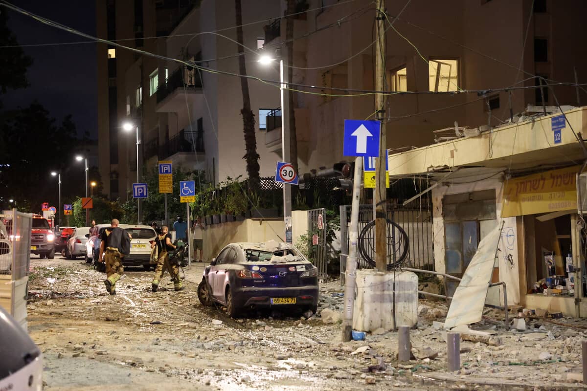 Members of the Israeli security forces walk along a debris-strewn street in Tel Aviv, after it was hit by a rocket fired by Palestinian militants from the Gaza Strip on October 7, 2023. - Palestinian militant group Hamas launched a surprise large-scale attack against Israel on October 7, firing thousands of rockets from Gaza and sending fighters to kill or abduct people as Israel retaliated with devastating air strikes. (Photo by JACK GUEZ / AFP)