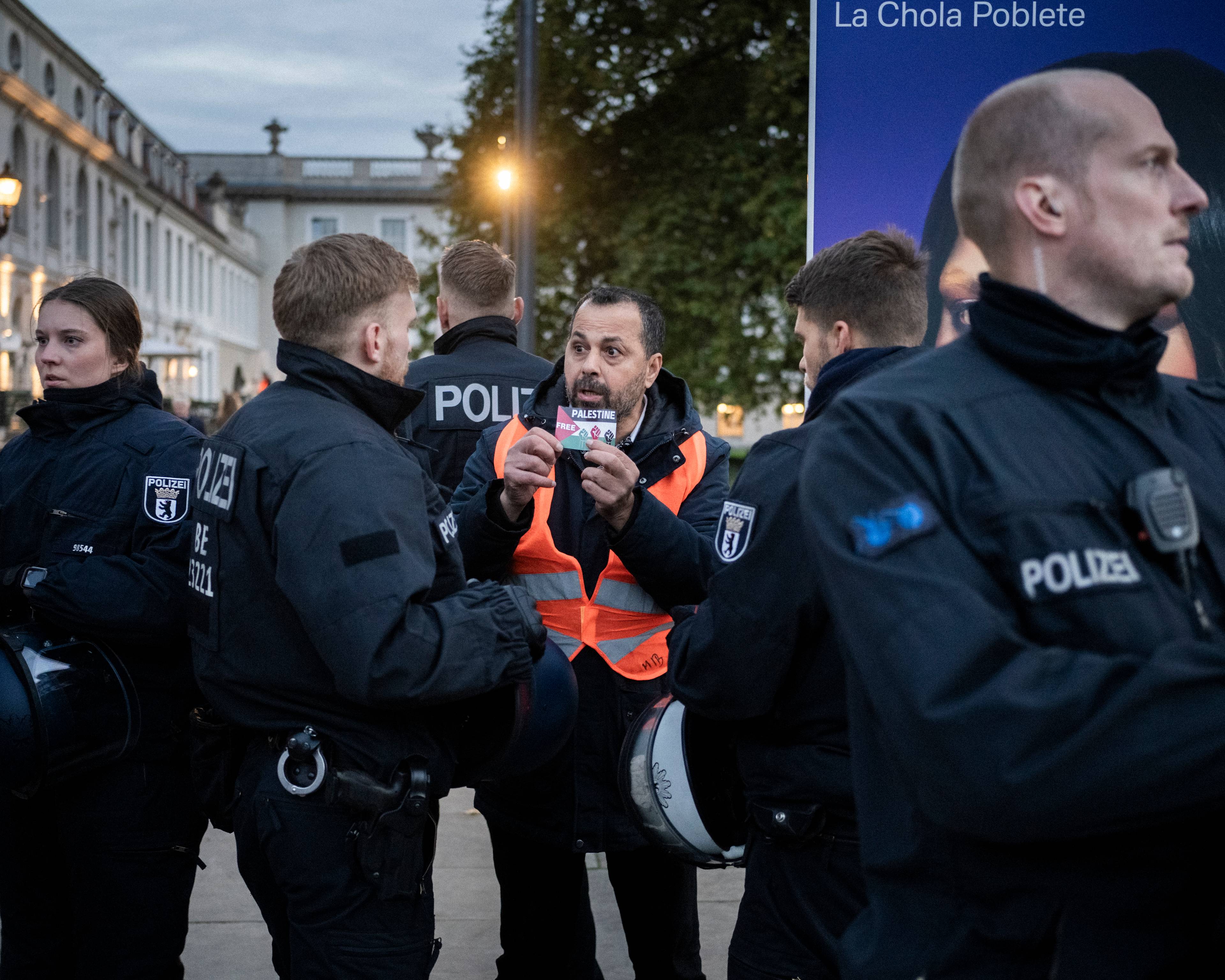 Niemieccy policjanci zatrzymują protestującego w pomarańczowej kamizelce