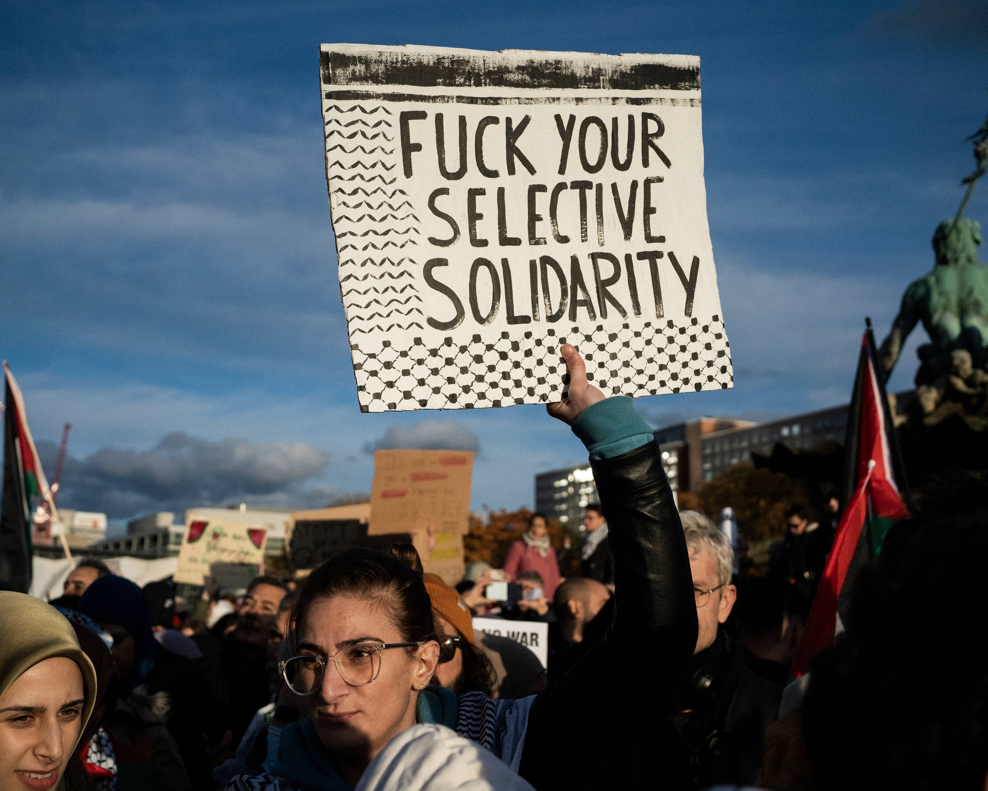 ktoś w tłumie unosi czarno-biały baner z napisem "Fuck your selektive solidarity"