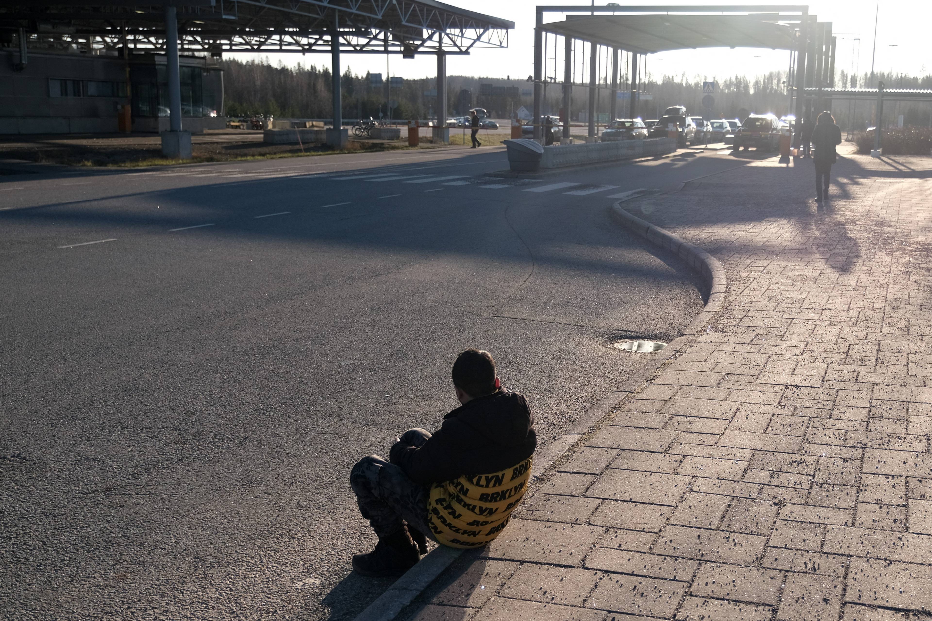 Osoba ubiegająca się o azyl siedzi na ziemi w pobliżu przejścia granicznego Nuijamaa między Finlandią a Rosją, w Lappeenranta, w południowo-wschodniej Finlandii, 17 listopada 2023 r., po tym jak fiński rząd ogłosił zamknięcie czterech z ośmiu wschodnich przejść granicznych z Rosją