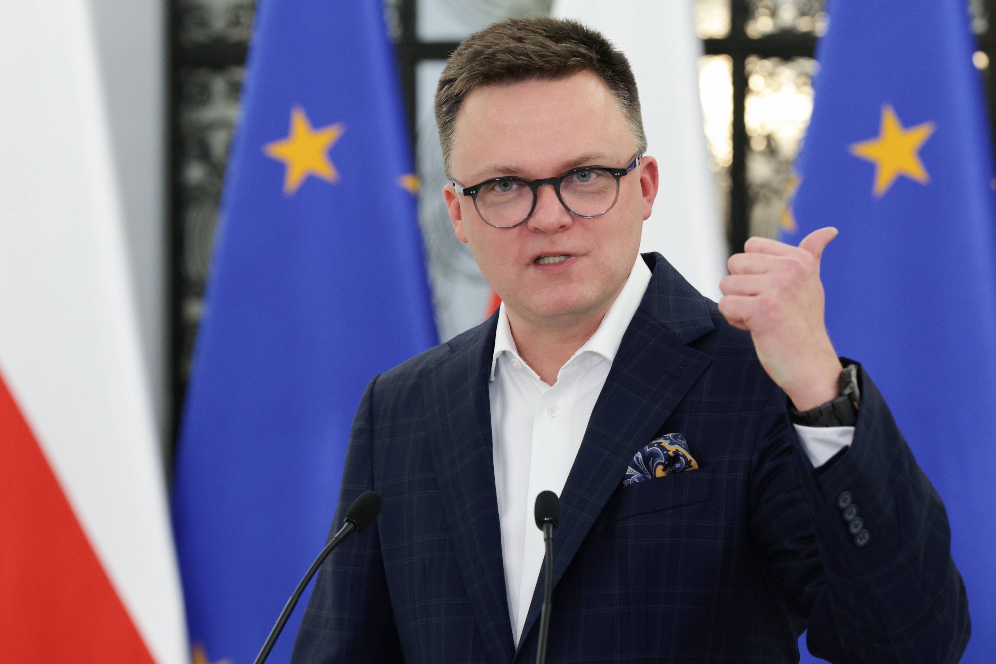Marszałek Sejmu Szymon Hołownia na tle flag unijnych