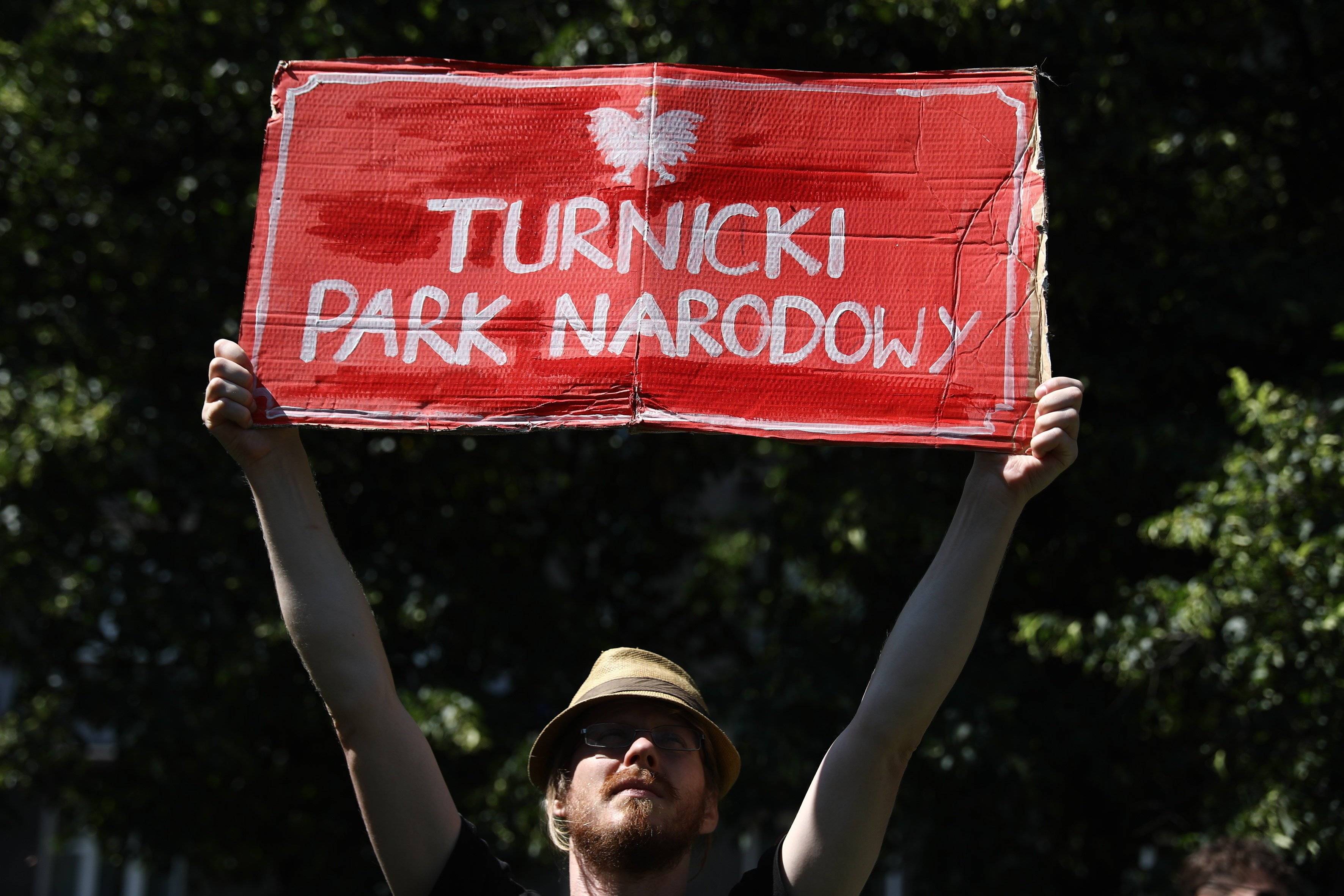 mężczyzna trzymający transparent ze znakiem "Turnicki Park Narodowy"