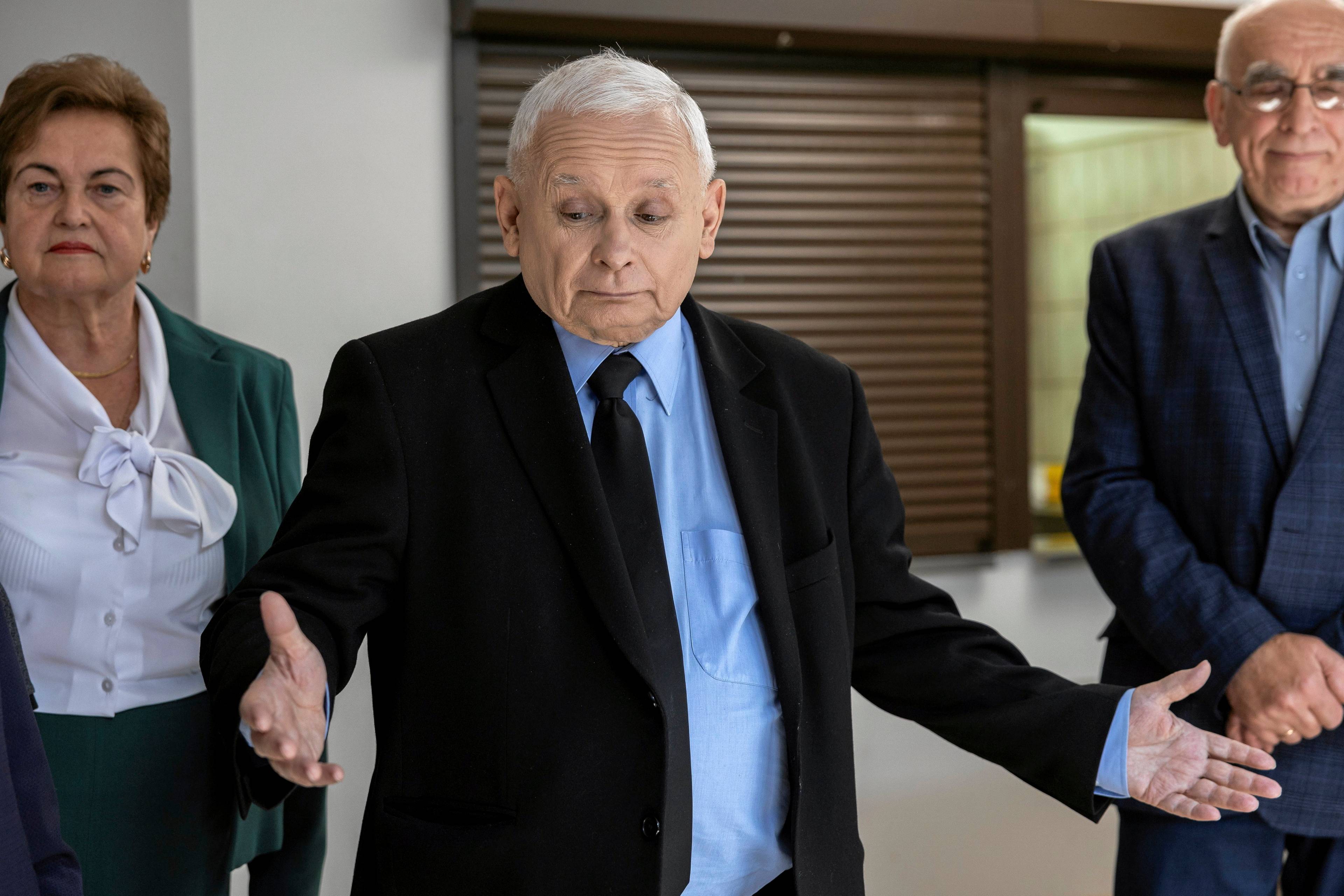 Jarosław Kaczyński stoi z rozłożonymi rękami i zdziwioną miną