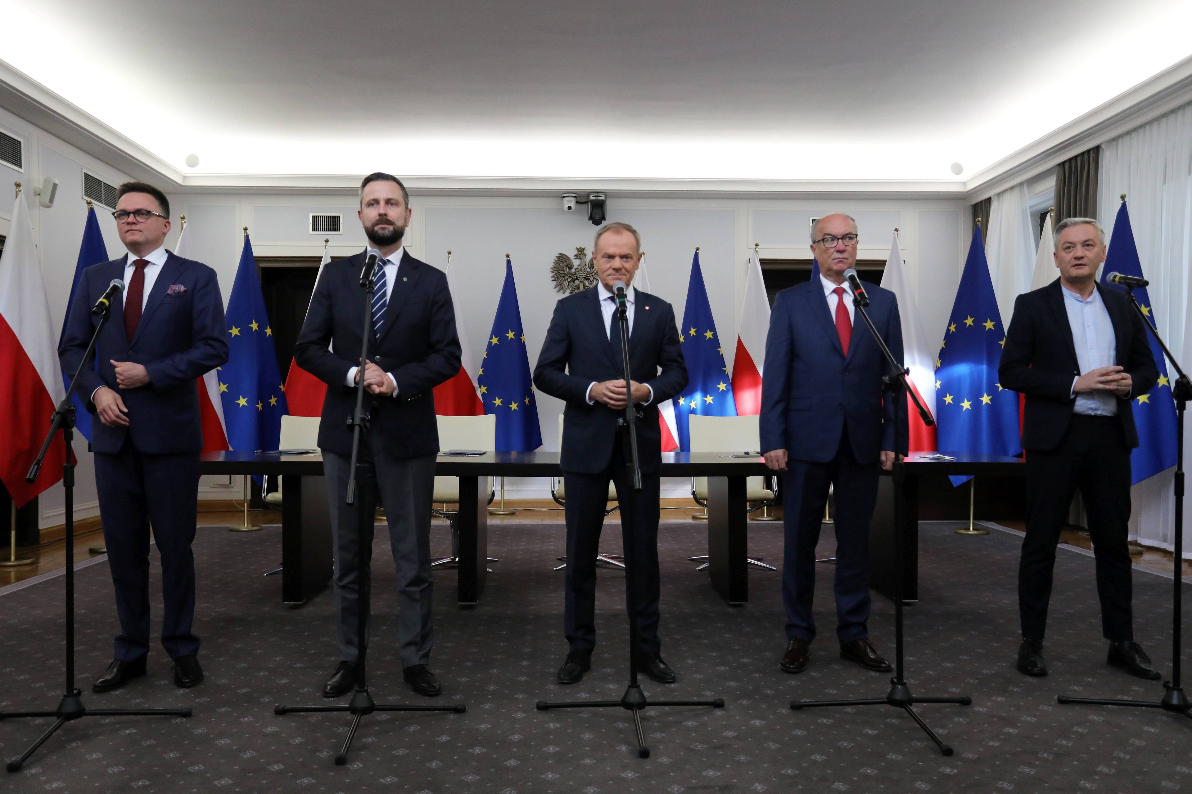 Pięciu liderów przyszłej koalicji rządowej stoi w jednej linii przed mikrofonami na konferencji prasowej po podpisaniu umowy koalicyjnej