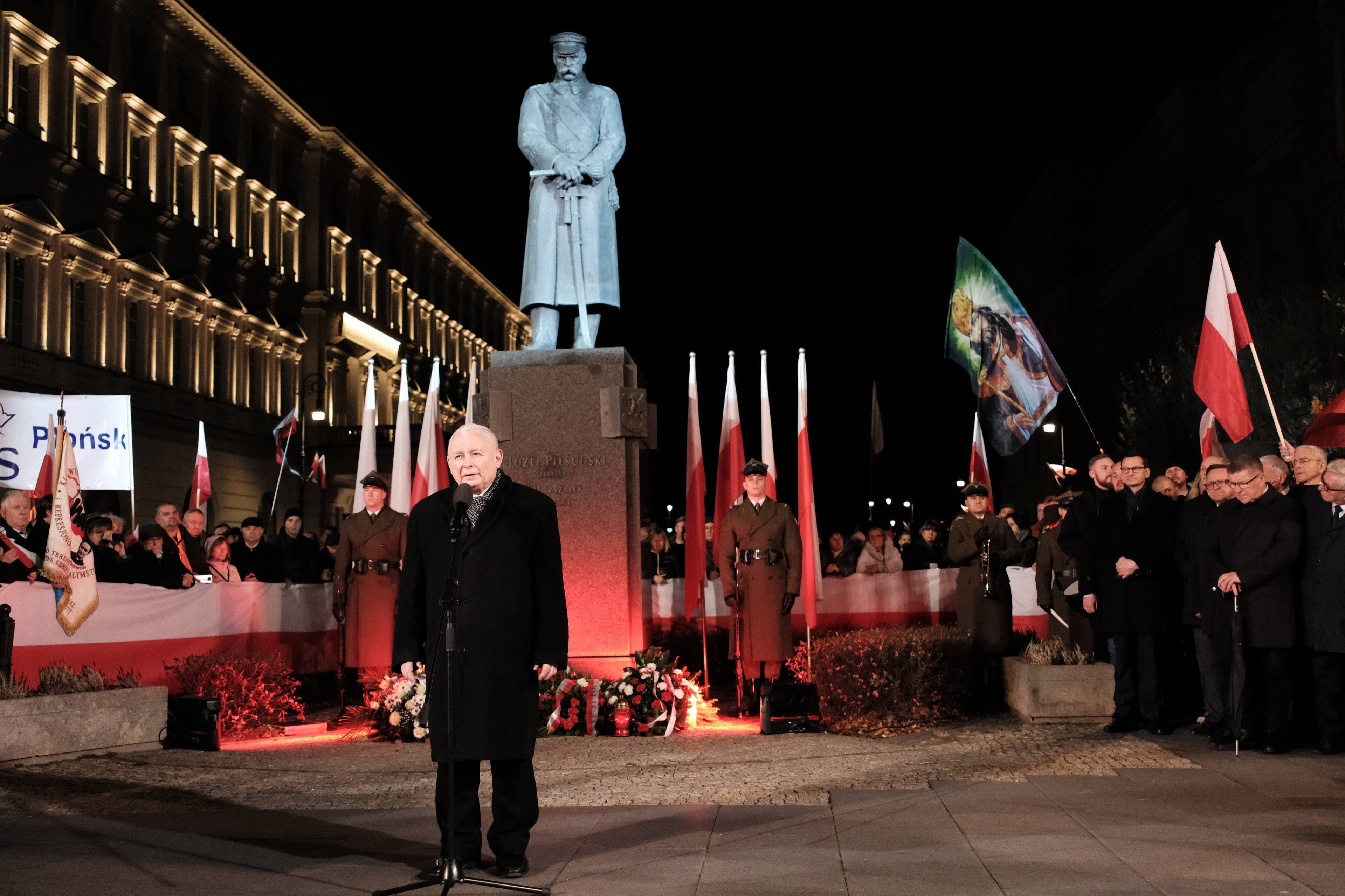 Mężczyan wieczorem przemawia na placu Piłsudskiego