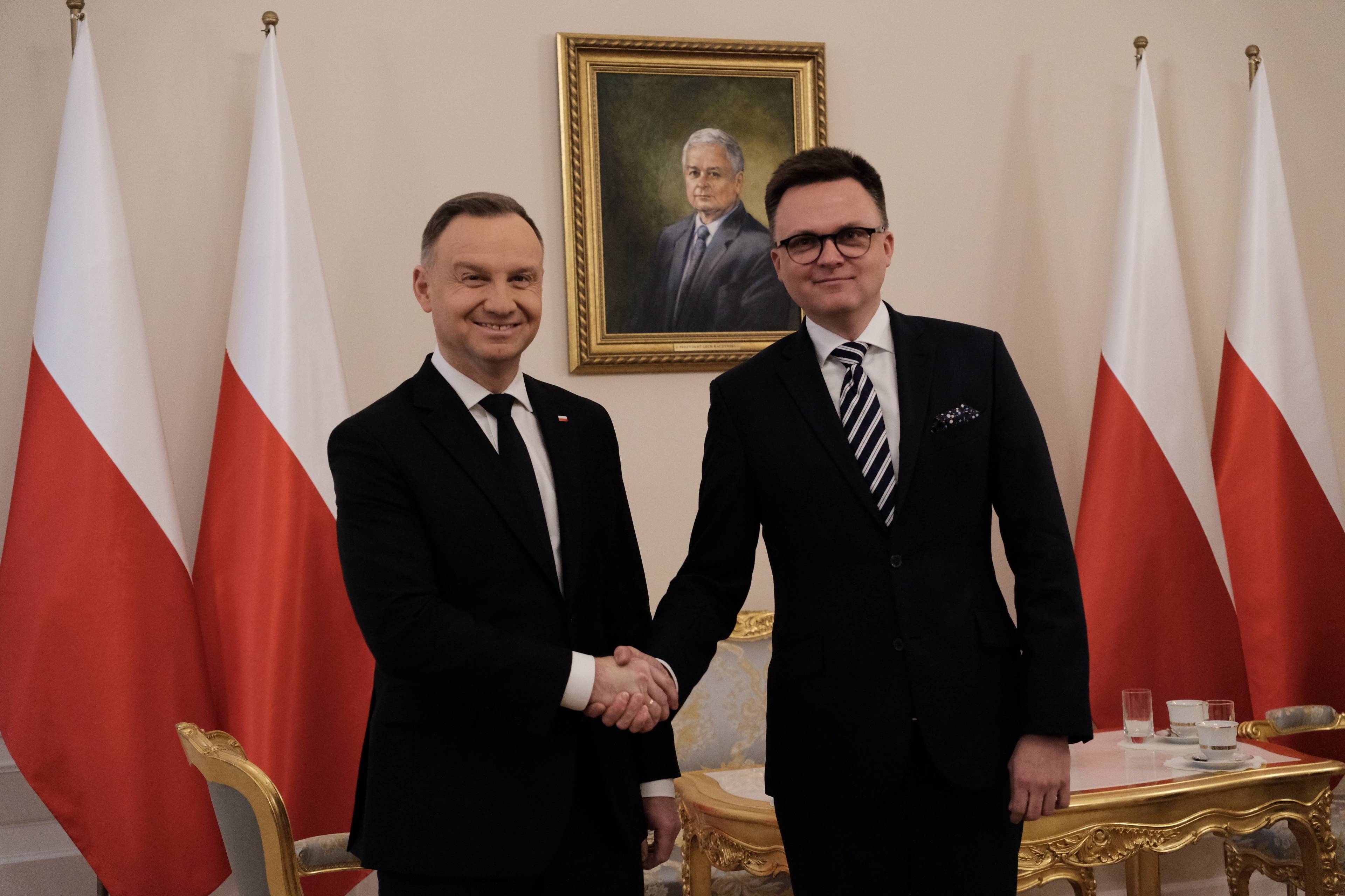 Duda i Hołownia na tle polskich flag