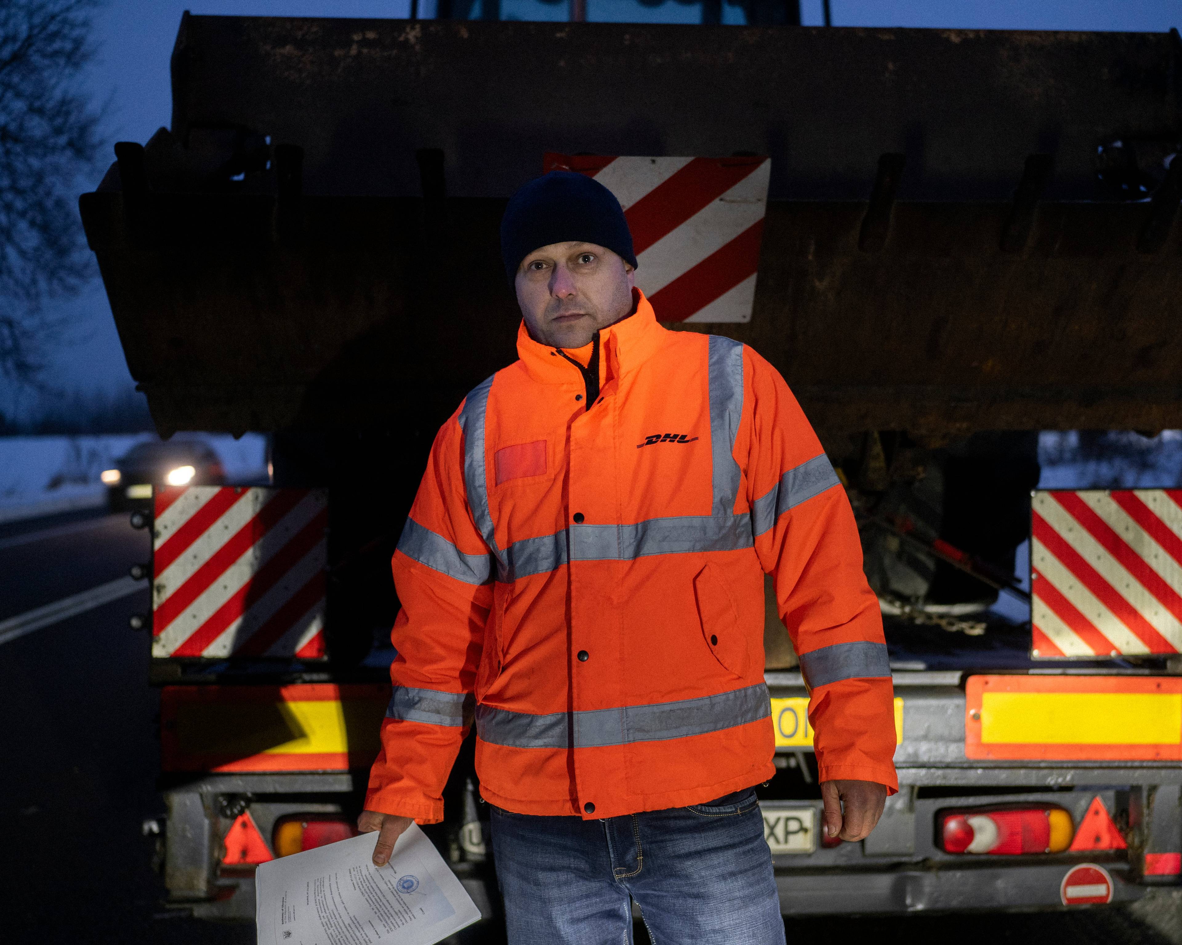 Mężczyzna w pomarańczowej kurtce przed ciężarówką