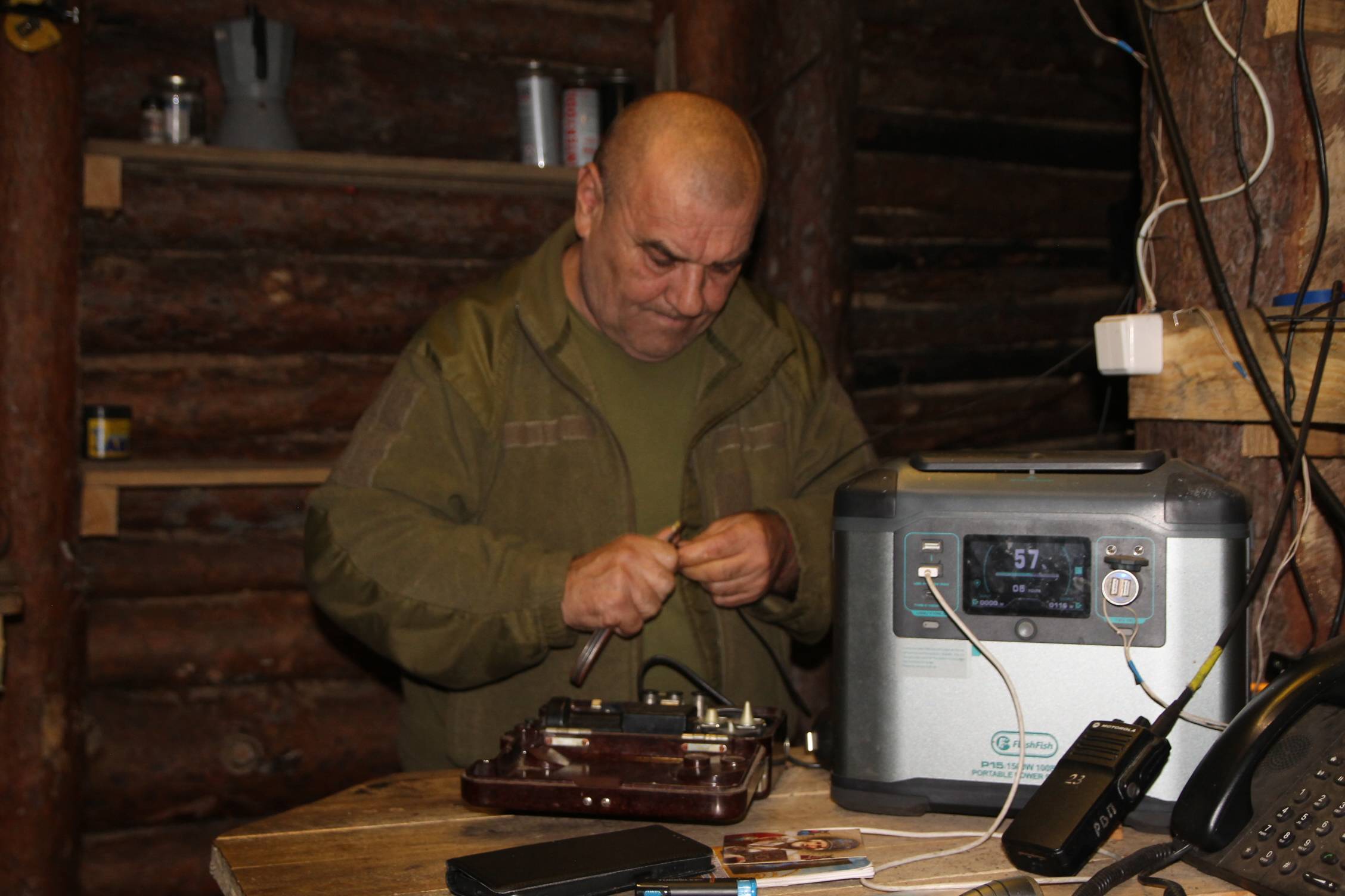 wnętrze okopu - ziemianki, żołnierz naprawia radiostację