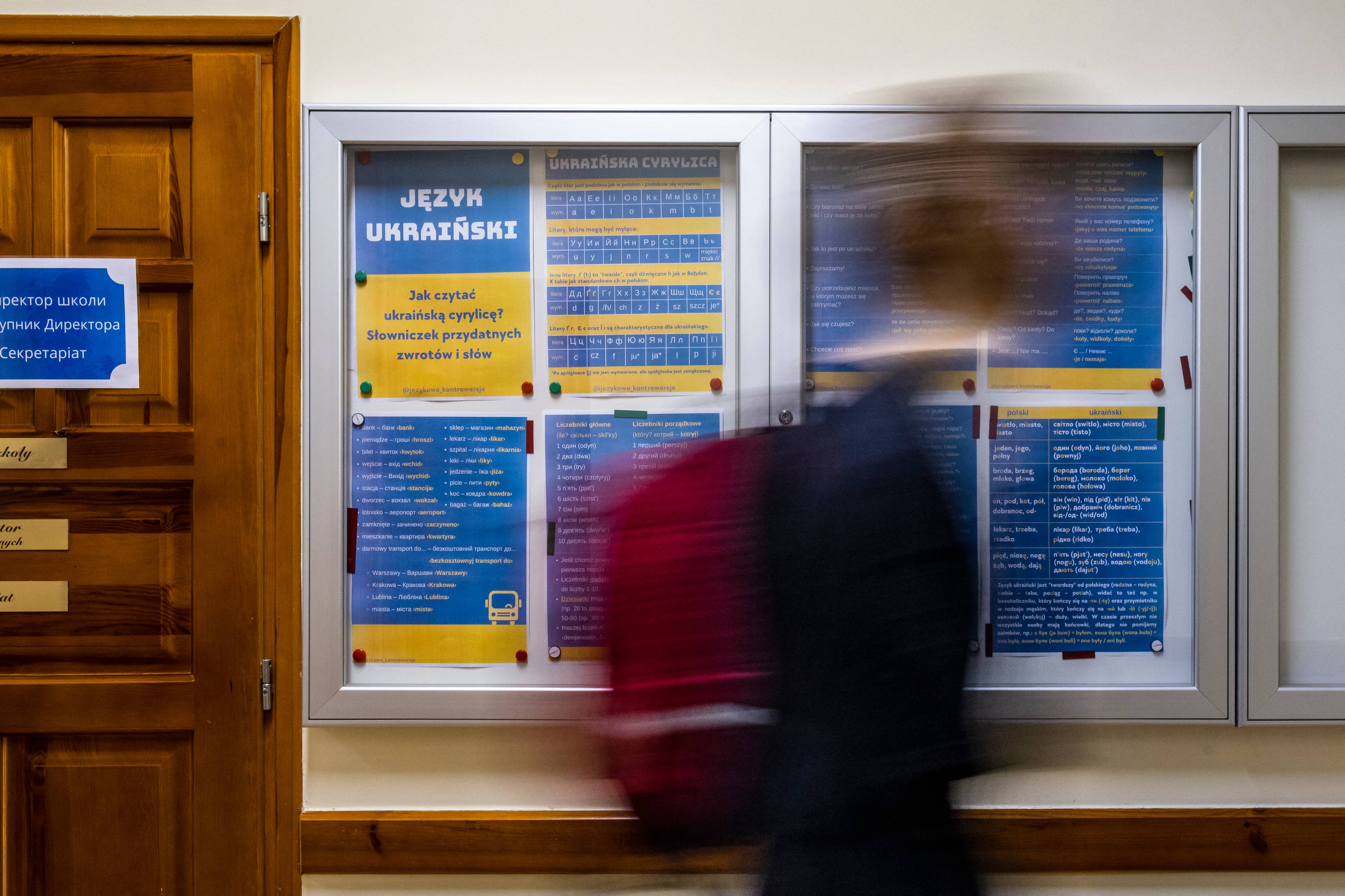 Uczeń przechodzi obok tablicy z gramatyką w języku ukraińskim i polskim na korytarzu liceum.