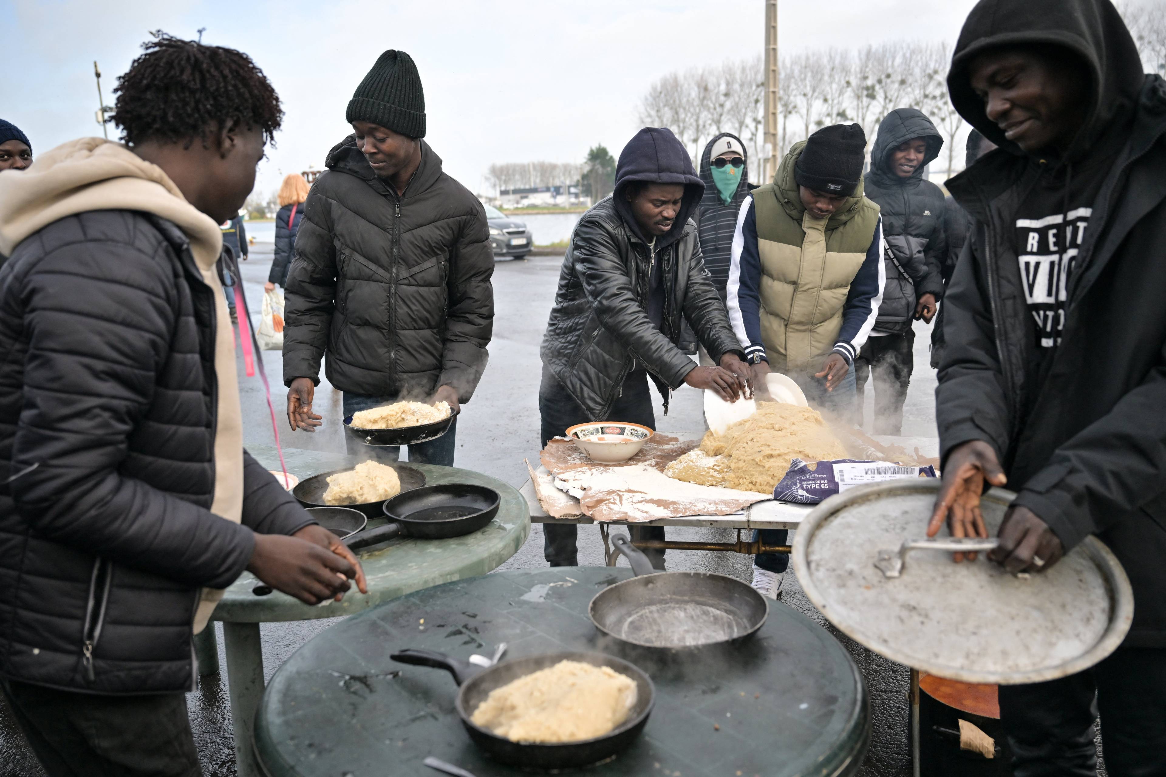 Czarnoskórzy migranci z Sudanu we Francji przygotowują wspólnie posiłek