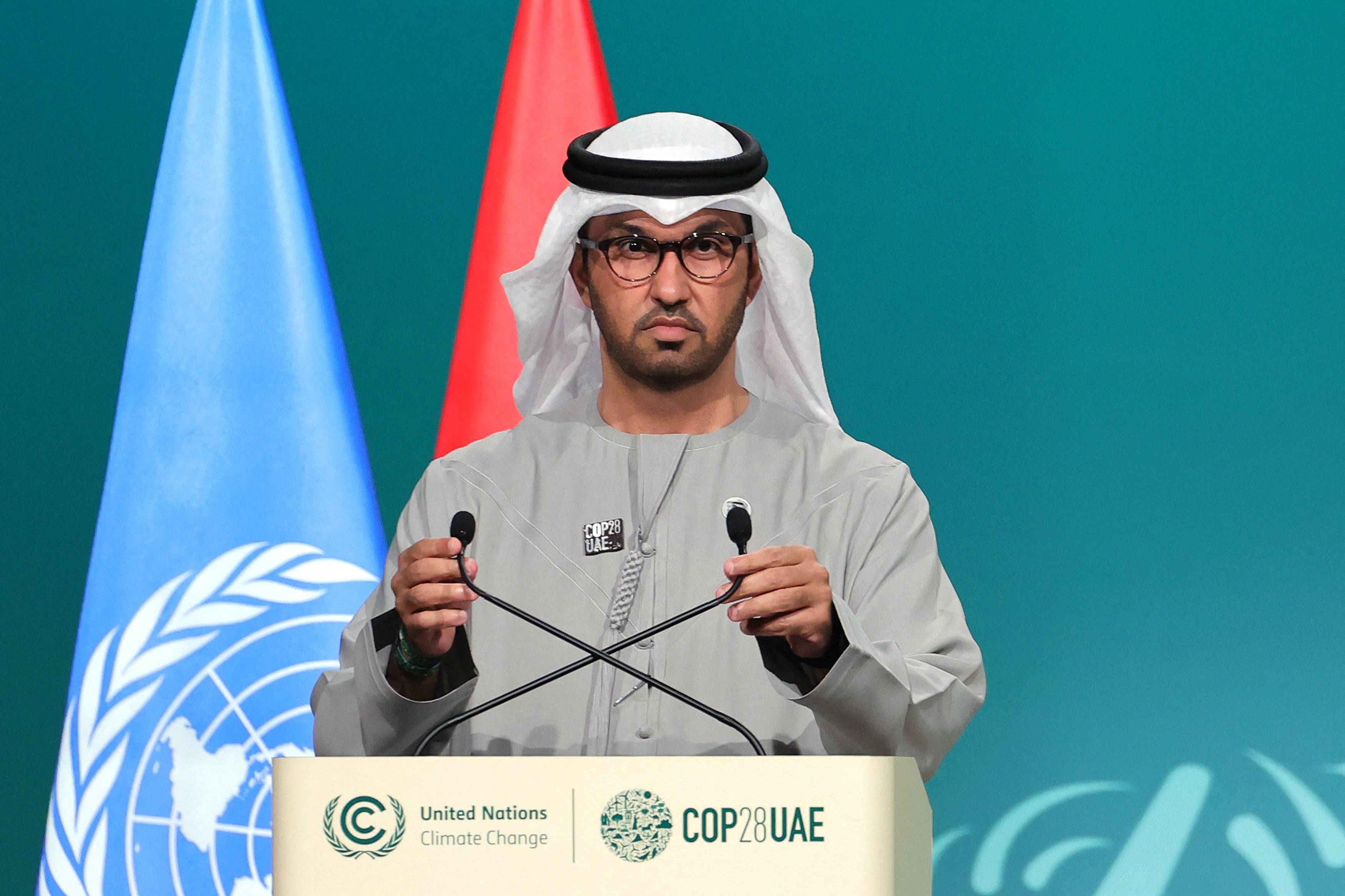 COP28 president Sultan Ahmed Al Jaber adjusts his microphone during a plenary session at the United Nations climate summit in Dubai on December 13, 2023. - Nations adopted the first ever UN climate deal that calls for the world to transition away from fossil fuels. "We have the basis to make transformational change happen," COP28 president Sultan Al Jaber said at the UN climate summit in Dubai before the deal was adopted by consensus, prompting delegates to rise and applaud. (Photo by Giuseppe CACACE / AFP)