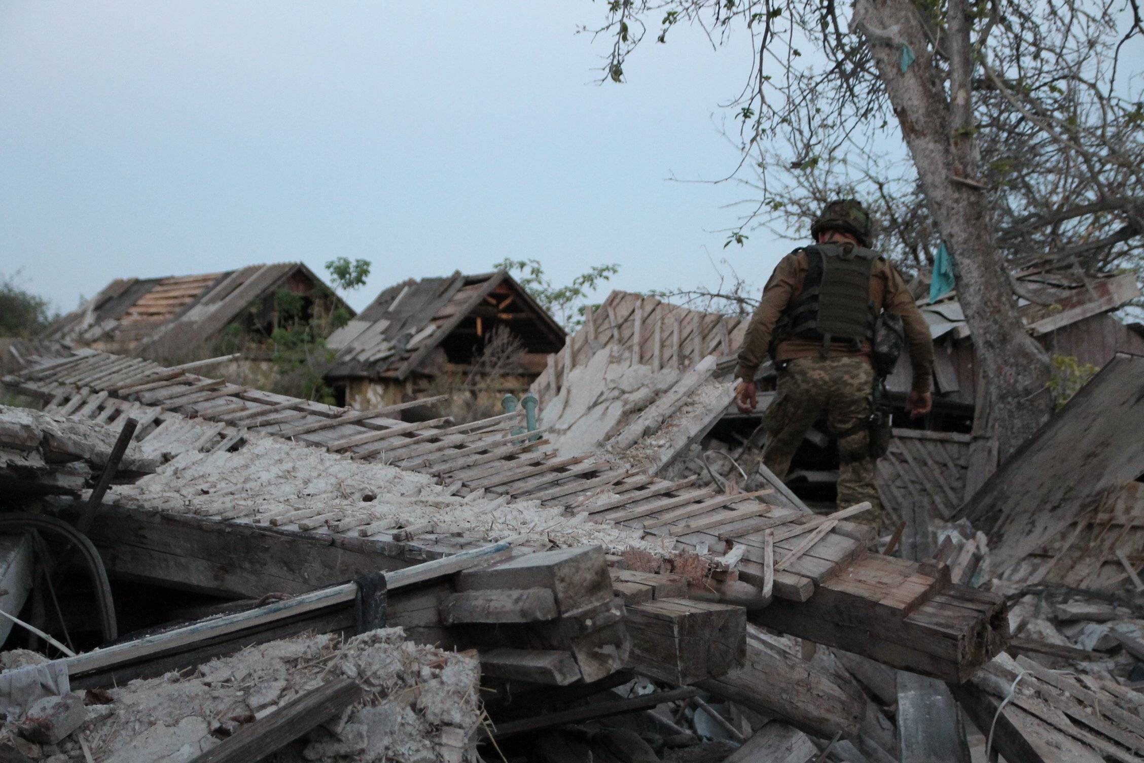 żołnierz piechoty chodzi wśród ruin wiejskich domów