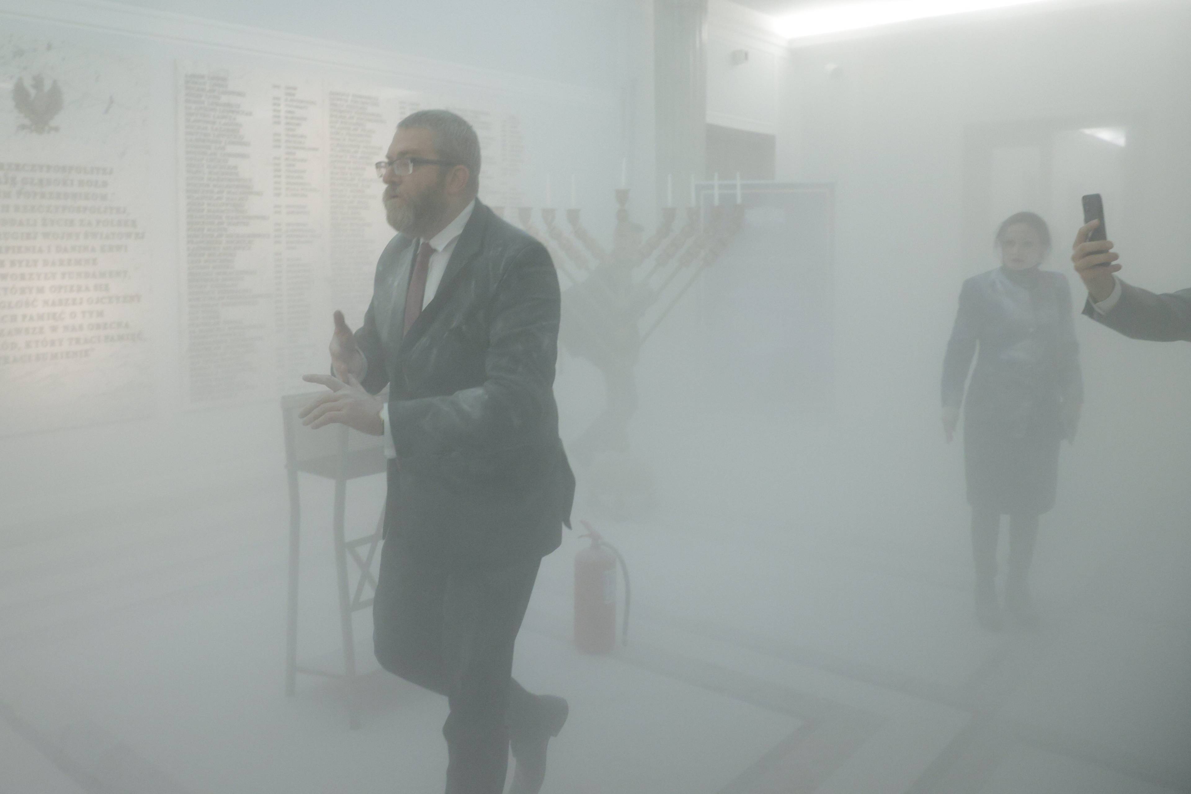 Grzegorz Braun w oparach białego pyłu na korytarzu sejmowym