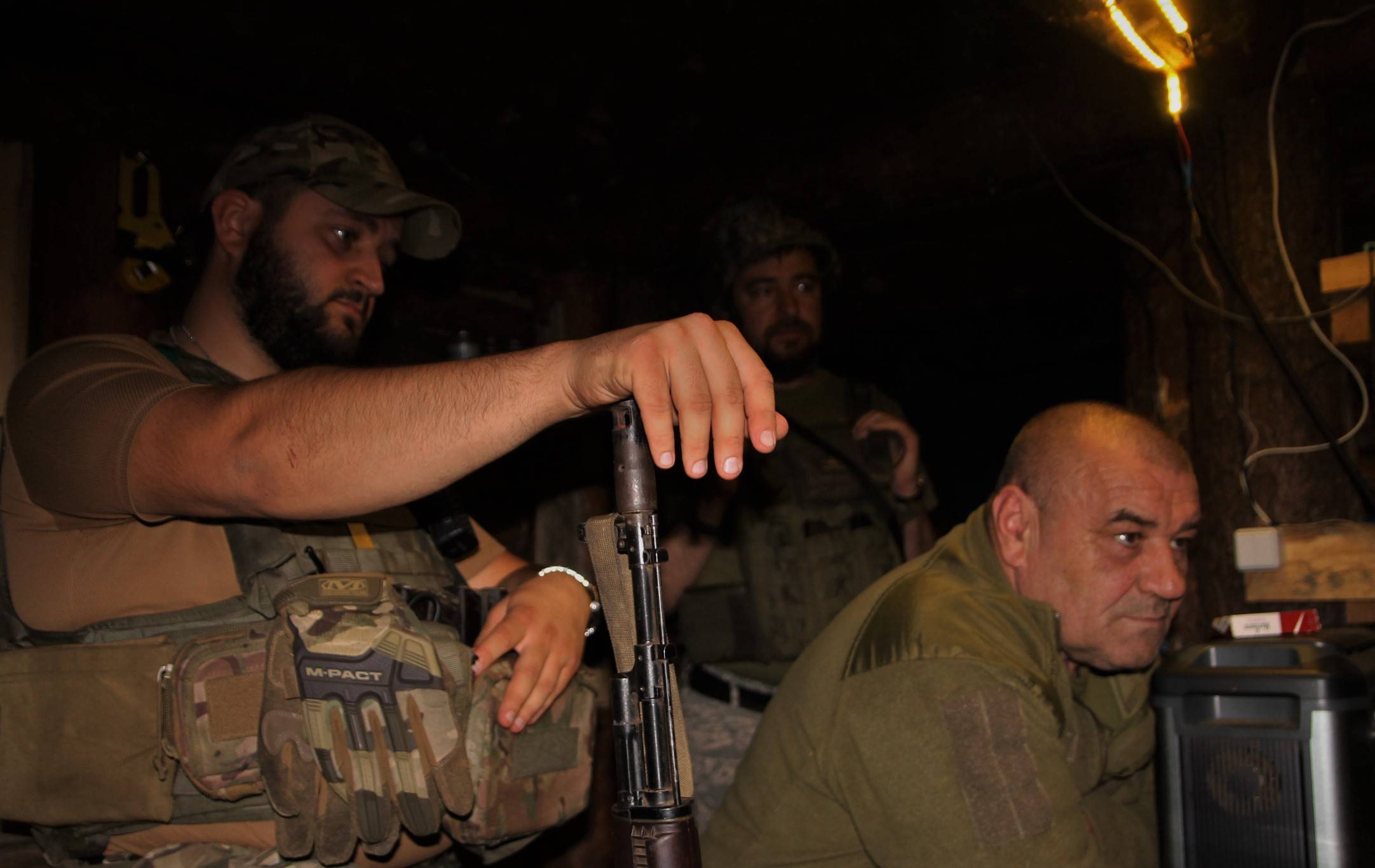zdjęcie wnętrza okopu, trzej żołnierze, jeden oparł rękę na lufie karabinu