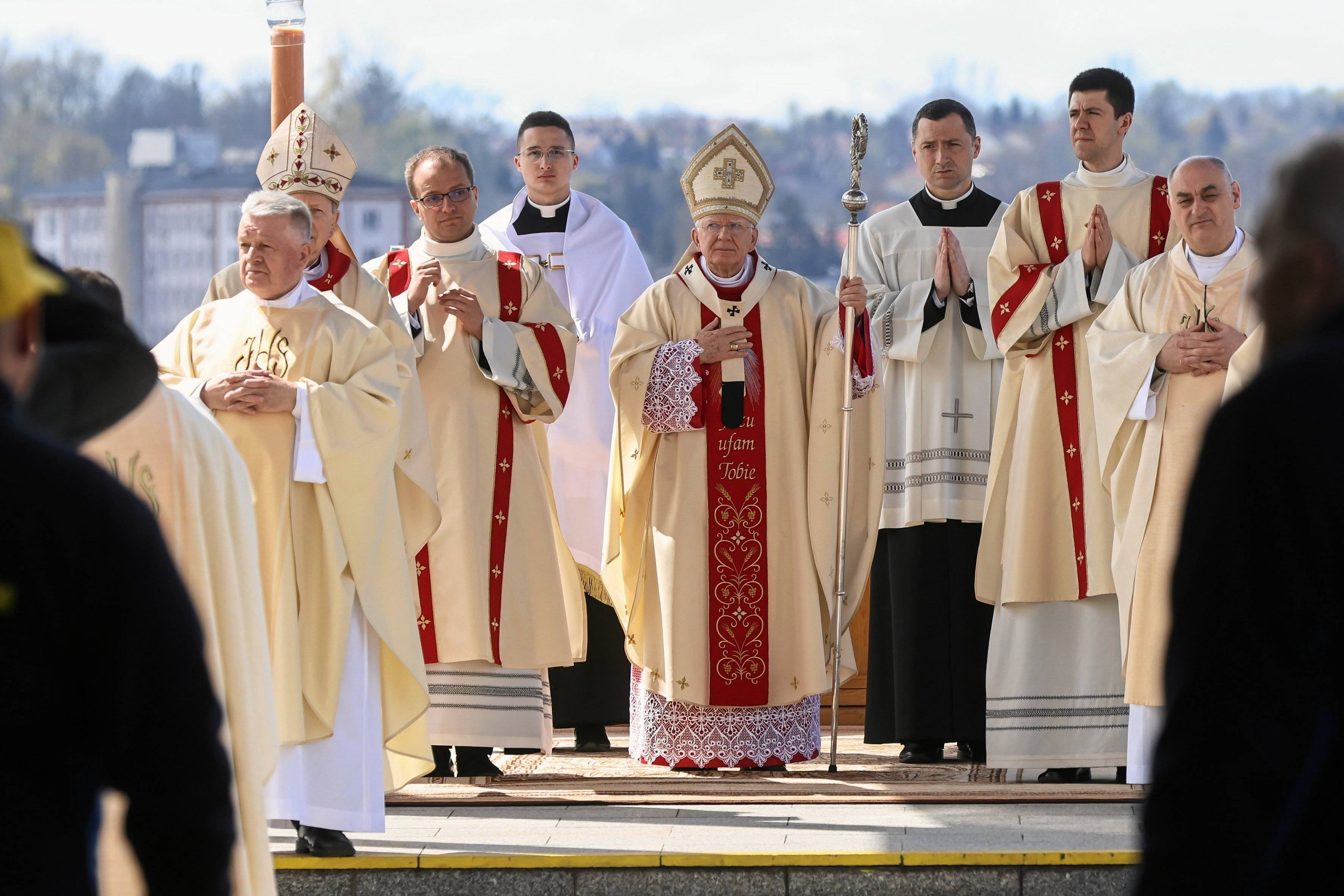 Biskupi kościoła katolickiego w złotych szatach liturgicznych, ręce mają złożone do modlitwy