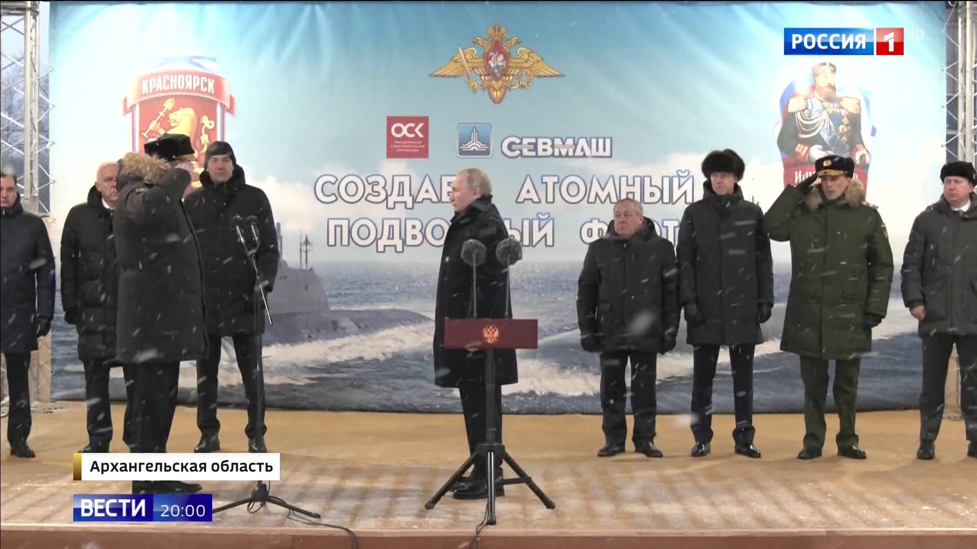 Putin odbiera meludnej męzczyzny w ciepłej kurtce, w tle zdjęcie łodzi podwodnej