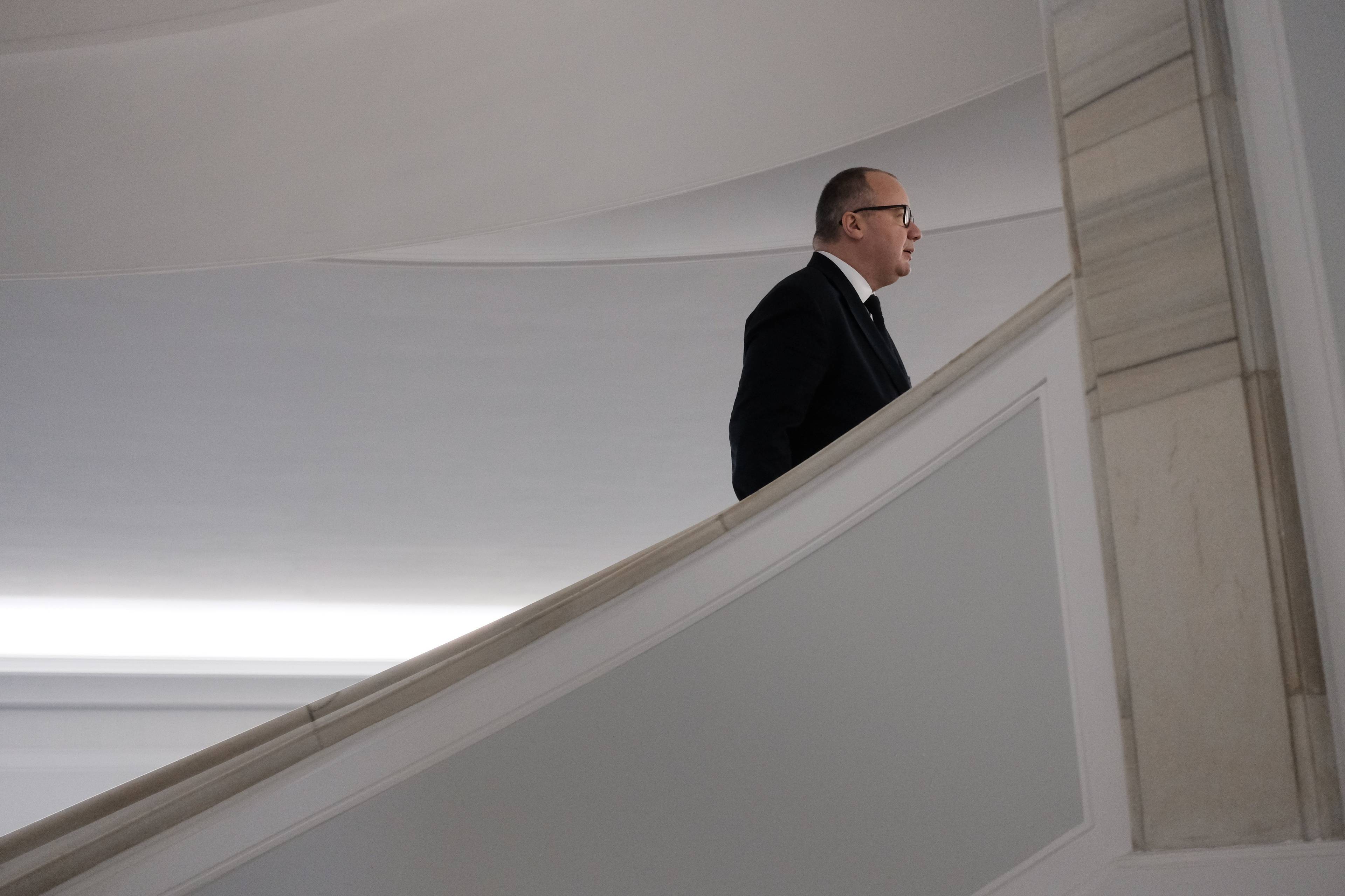 mężczyzna w garniturze i w okularach wchodzi po schodach