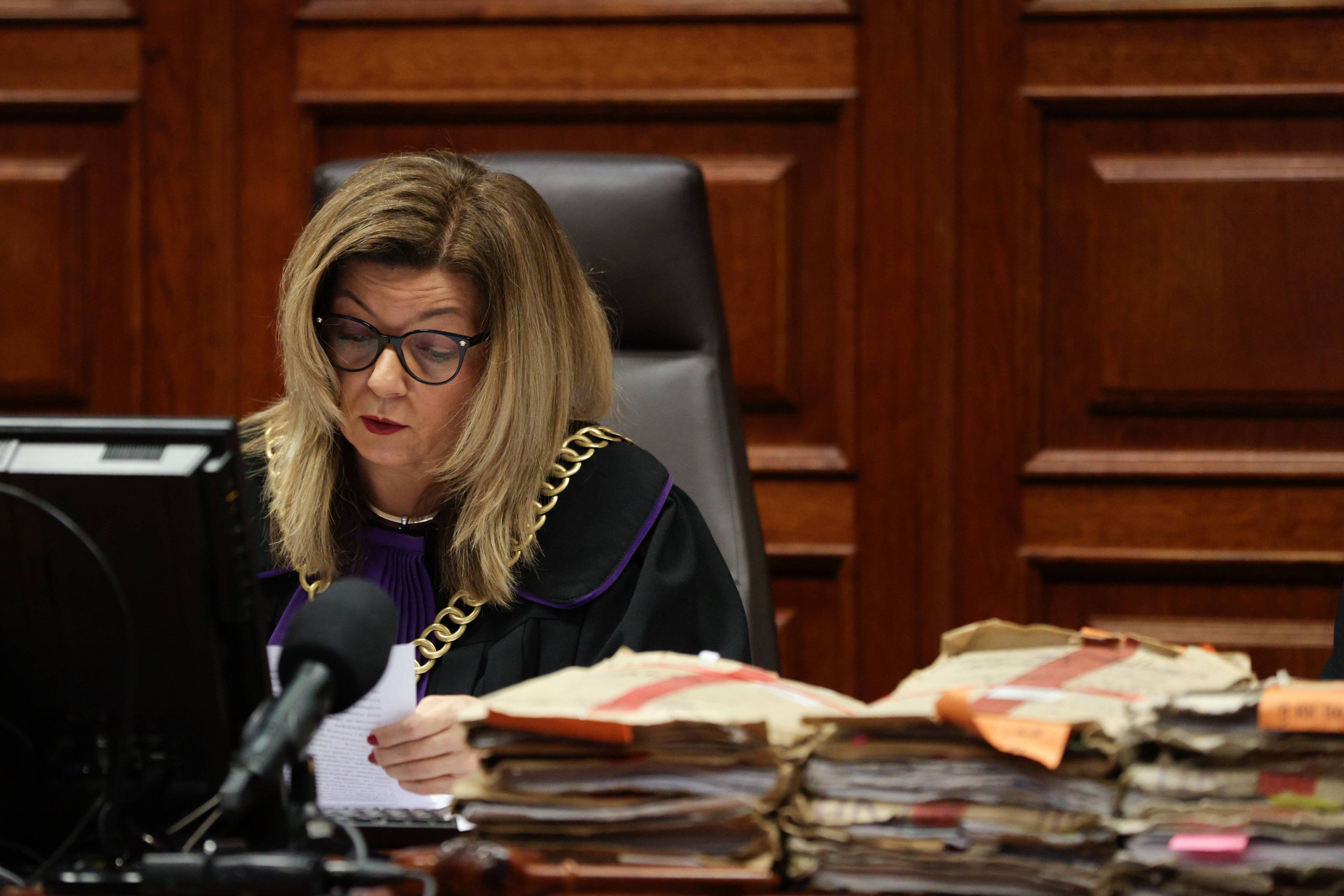 Sędzia Anna Bator-Ciesielska odczytuje wyrok za stołem, na którym leżą akta.